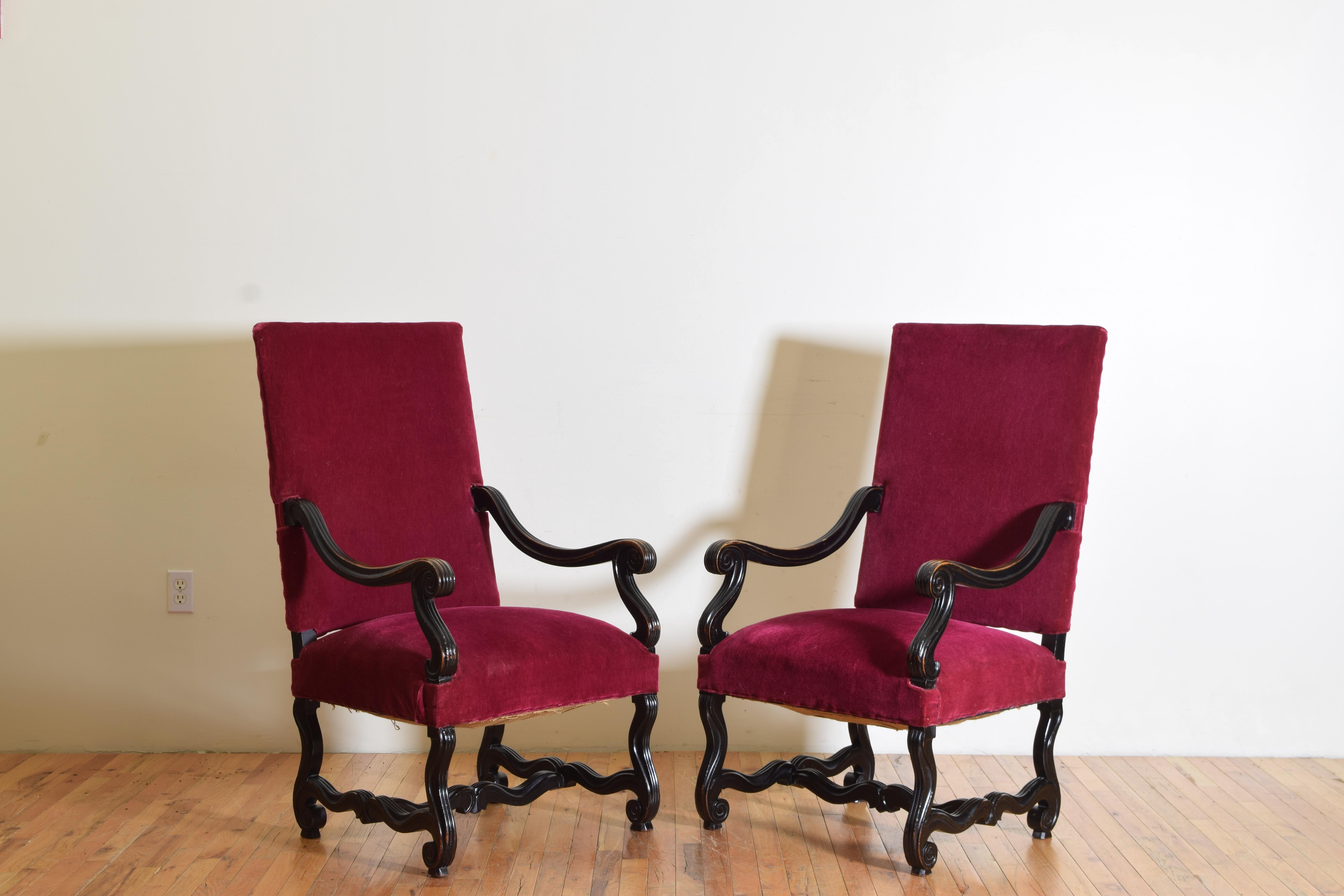 A pair of velvet upholstered, ebonized walnut and hand-carved armchairs in the Baroque style.