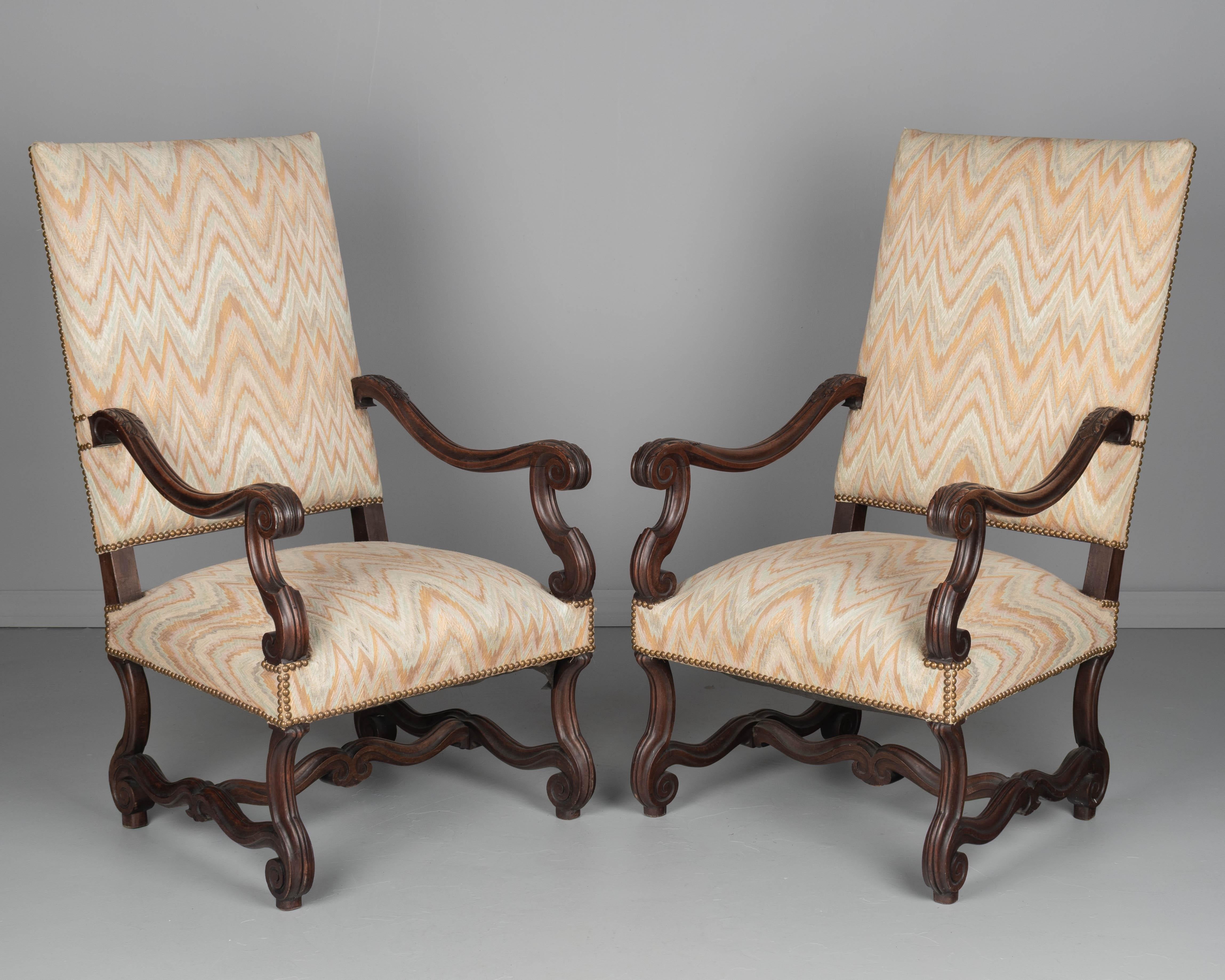 Ein Paar Fauteuils im Stil Louis XIV aus Nussbaum mit geschnitzten Details, stabiler Konstruktion und bequemen Sitzgelegenheiten. Die alte Polsterung mit Flammenstichmuster und Messingnägeln ist in gebrauchsfähigem Zustand. Circa 1960er