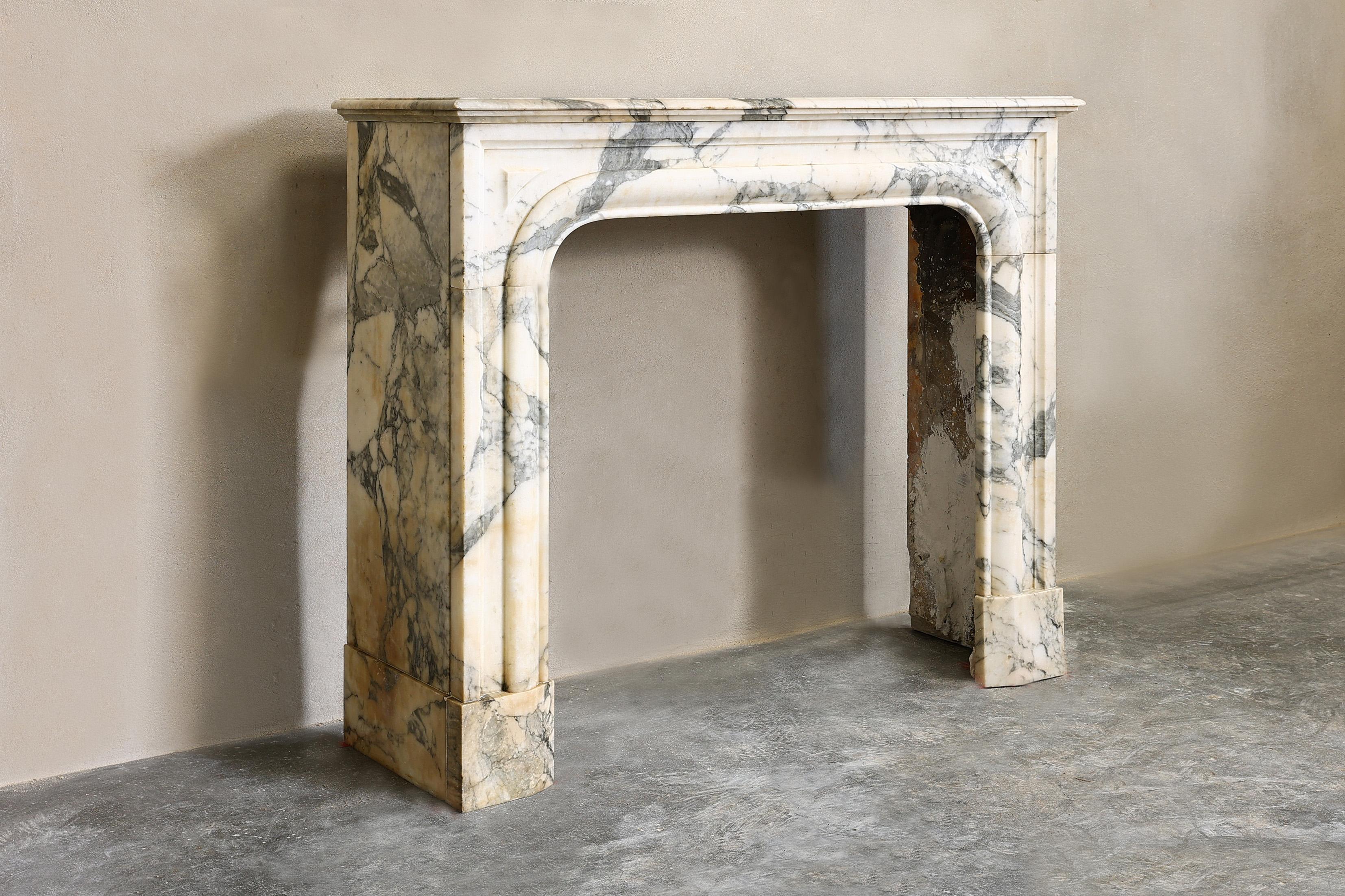 Very nice compact marble fireplace of Arabescato marble from Italy in style of Louis XIV. Arabescato is a white to cream-colored marble type that is always veined and that occurs in the Apennines north of Carrrara. The simple shape and color scheme