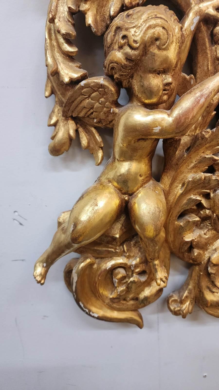 Antique giltwood mirror in the Louis XIV style, dating from the 19th century, with flowers and detail encircling the frame and two angels on the bottom and two on top. 