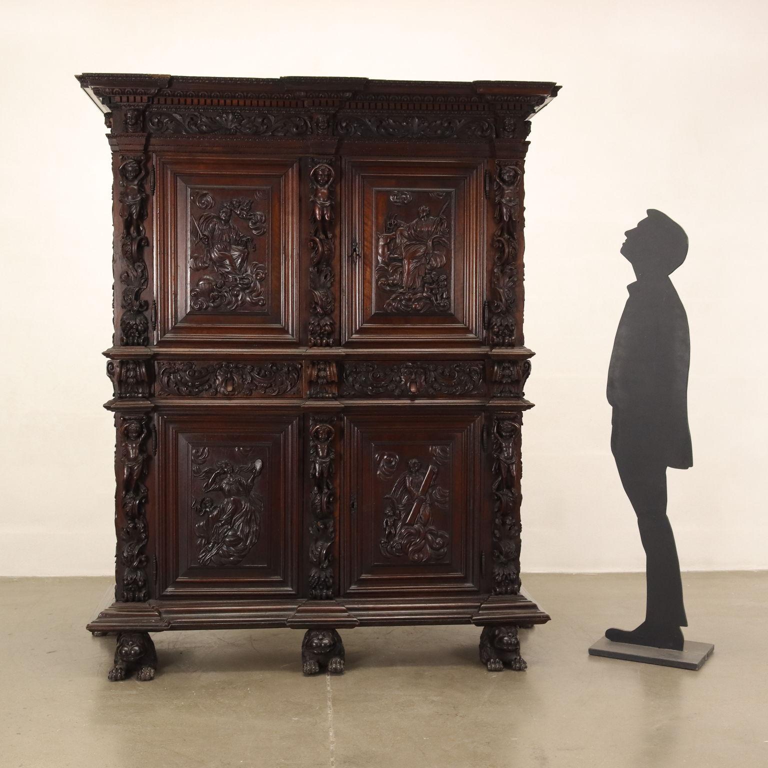 Louis XIV style sideboard supported by feet with lion features, has two doors surmounted by as many drawers and two other doors in the upper body. In walnut, it is entirely carved with leaf motifs and cherubs in the uprights, on the drawers there