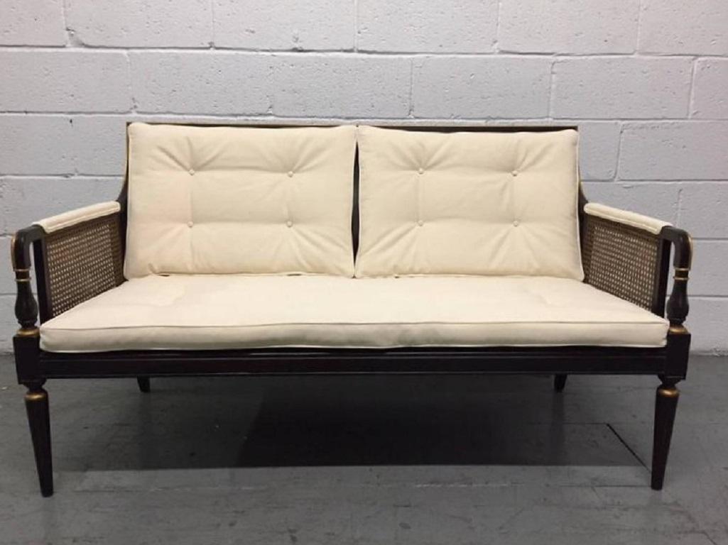 Louis XIV style sofa. Sofa has a painted black and gold frame, caned sides and back with linen upholstery. Has a loose cushioned seat. Back cushions are attached.
 