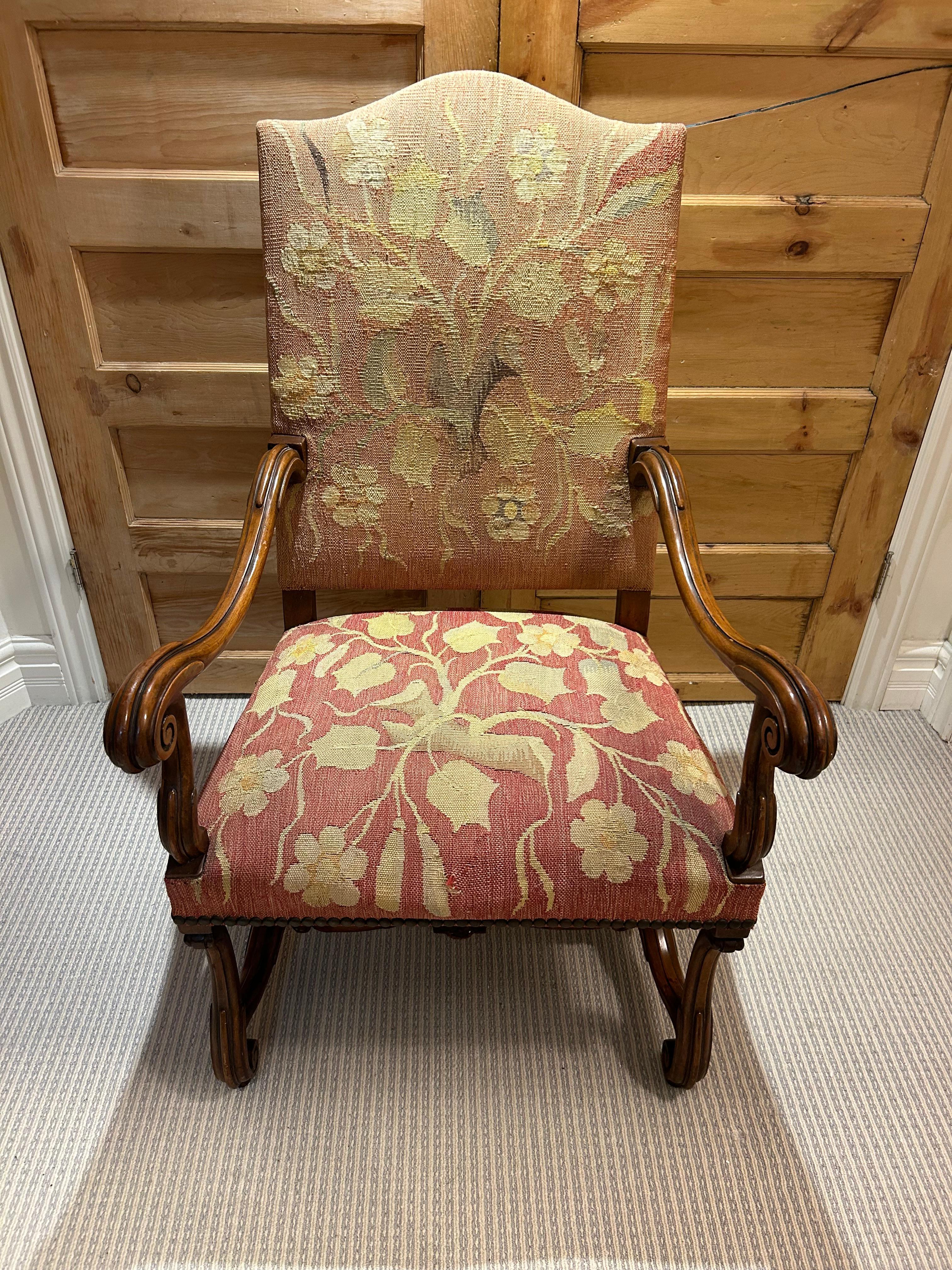 Uno spettacolare fauteuil francese del XIX secolo in stile Luigi XIV, rivestito con l'arazzo originale. Imbottitura in arazzo con dettagli borchiati su una struttura in noce con sostegni figurati.  L'arazzo raffigura deliziosi e sinuosi motivi di