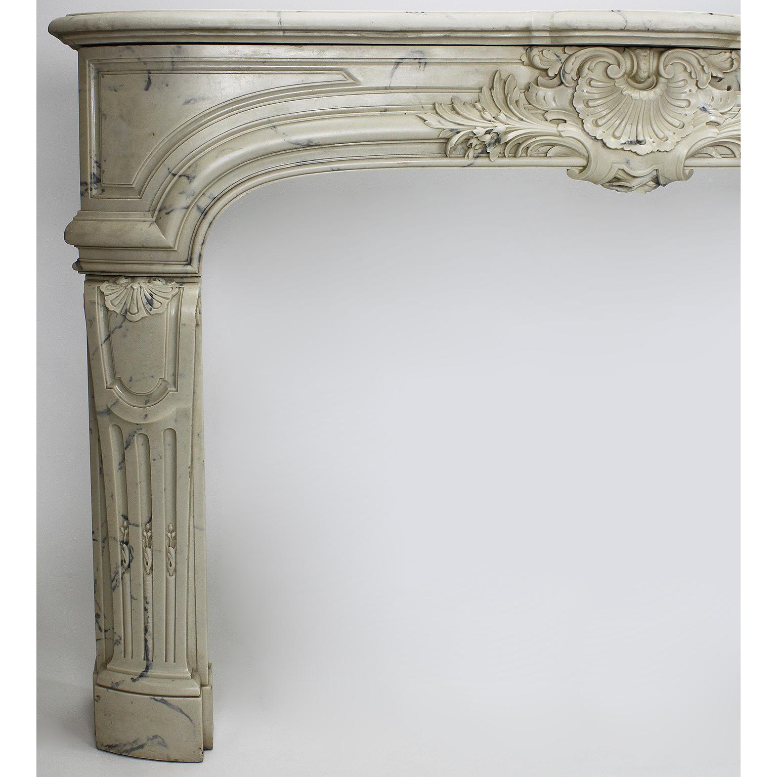 A Louis XIV style veined white cultured cast-marble fireplace mantel. The ornately detailed mantel centered with a seashell flaked by flowers and leaves, circa late 20th century.

Measures: 

Shelf width 67 3/8 inches (171.2 cm)
Shelf depth 12 1/2