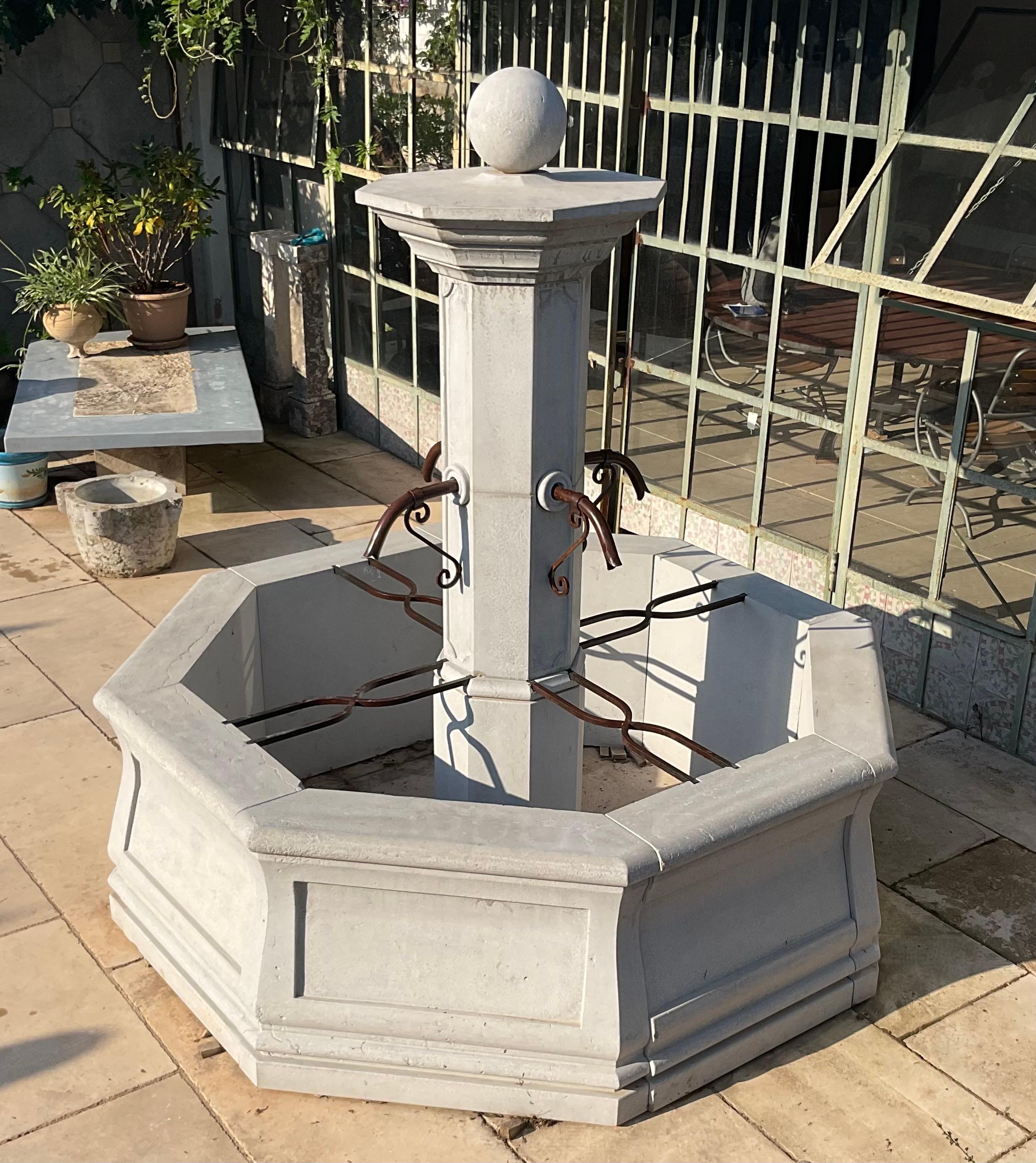 Elegante réédition d'une fontaine de village octogonale de style Louis XIV, finement réalisée en pierre calcaire portugaise de haute qualité et de haute densité, de couleur gris clair. Pour la finition et le vieillissement, la pierre a été poncée