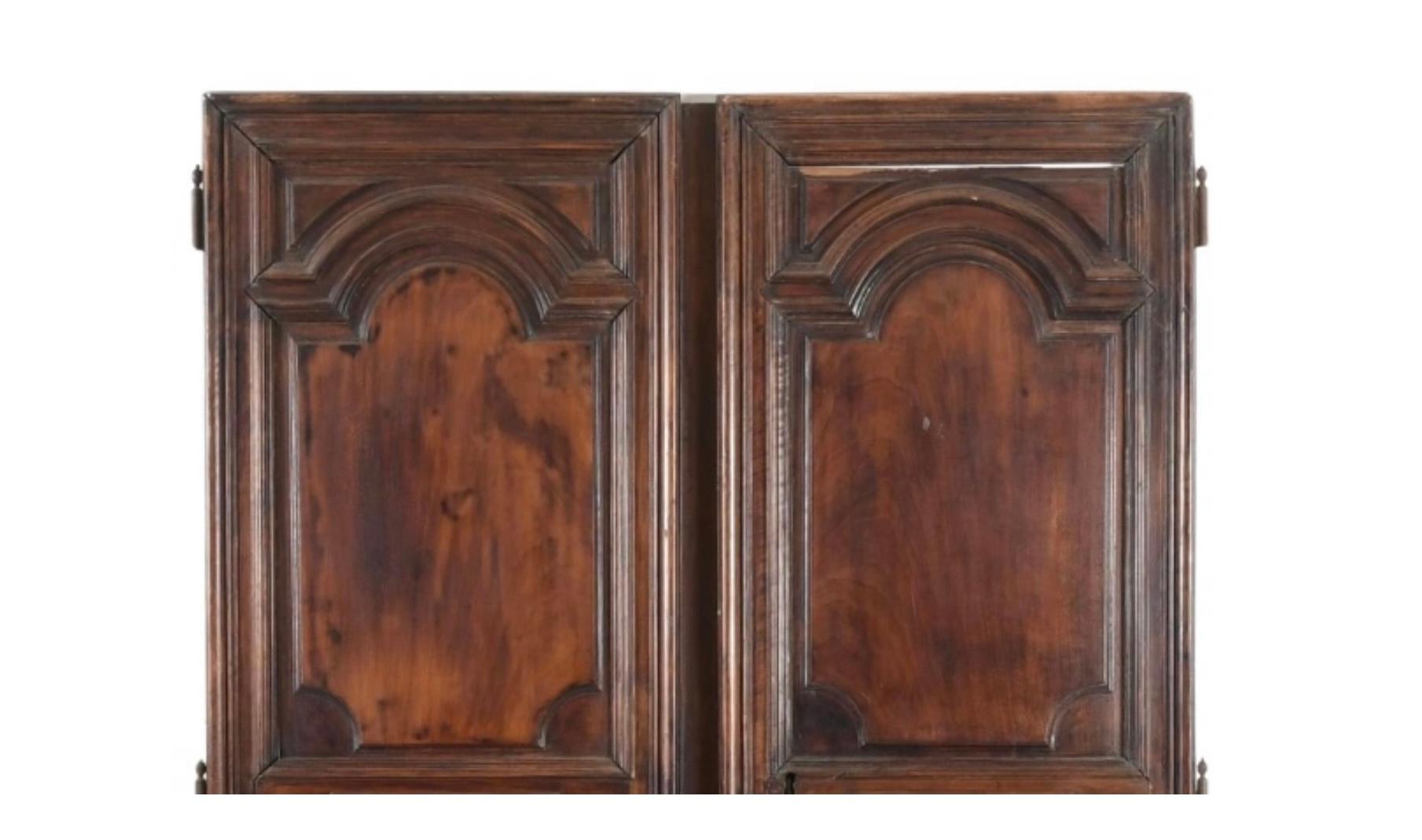 A Large Pair of Louis XIV Walnut Armoire Doors. Each door showcases deeply molded and arched raised panels with beautifully carved architectural details typical of the Louis XVI era. The walnut has developed a superb, warm surface with age,