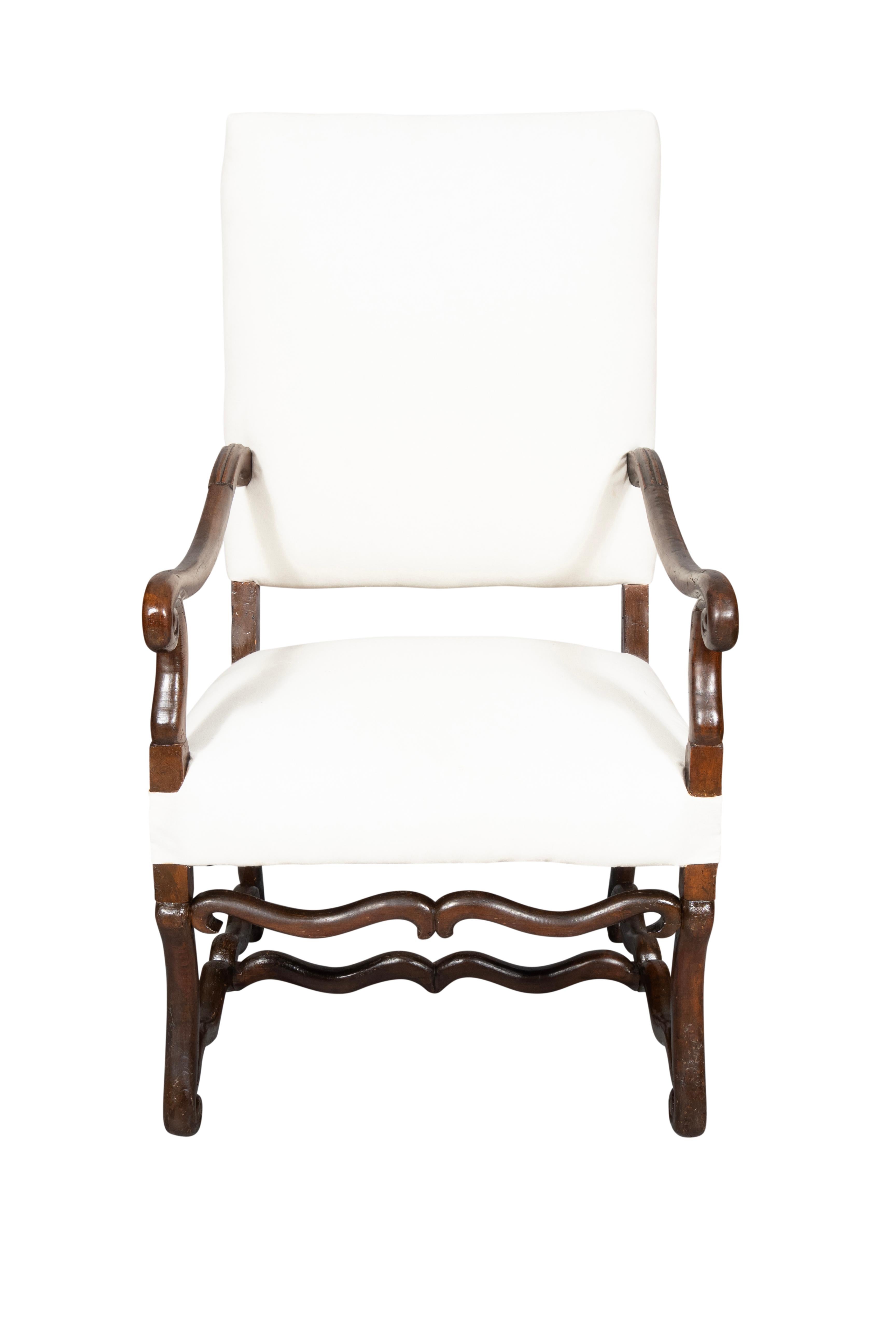 Dossier et assise hauts et carrés. Accoudoirs à volutes. Pieds courbes en S reliés par des traverses conformes.