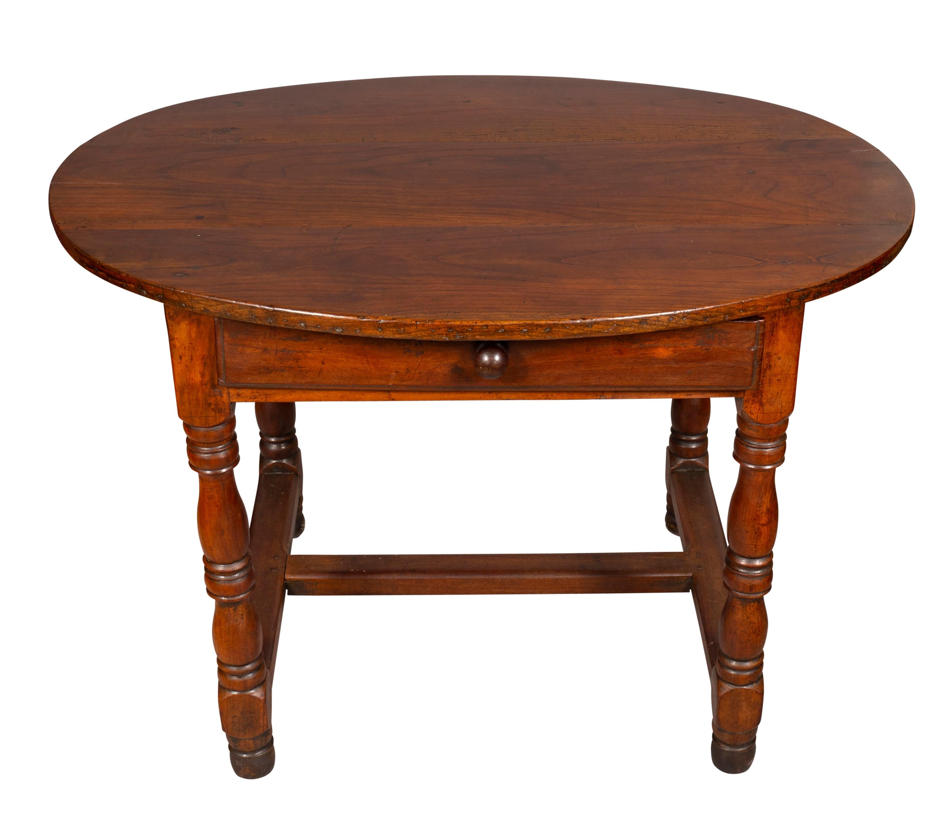 With an oval top possible replaced or reshaped over a drawer and raised on turned legs joined by an H form stretcher.