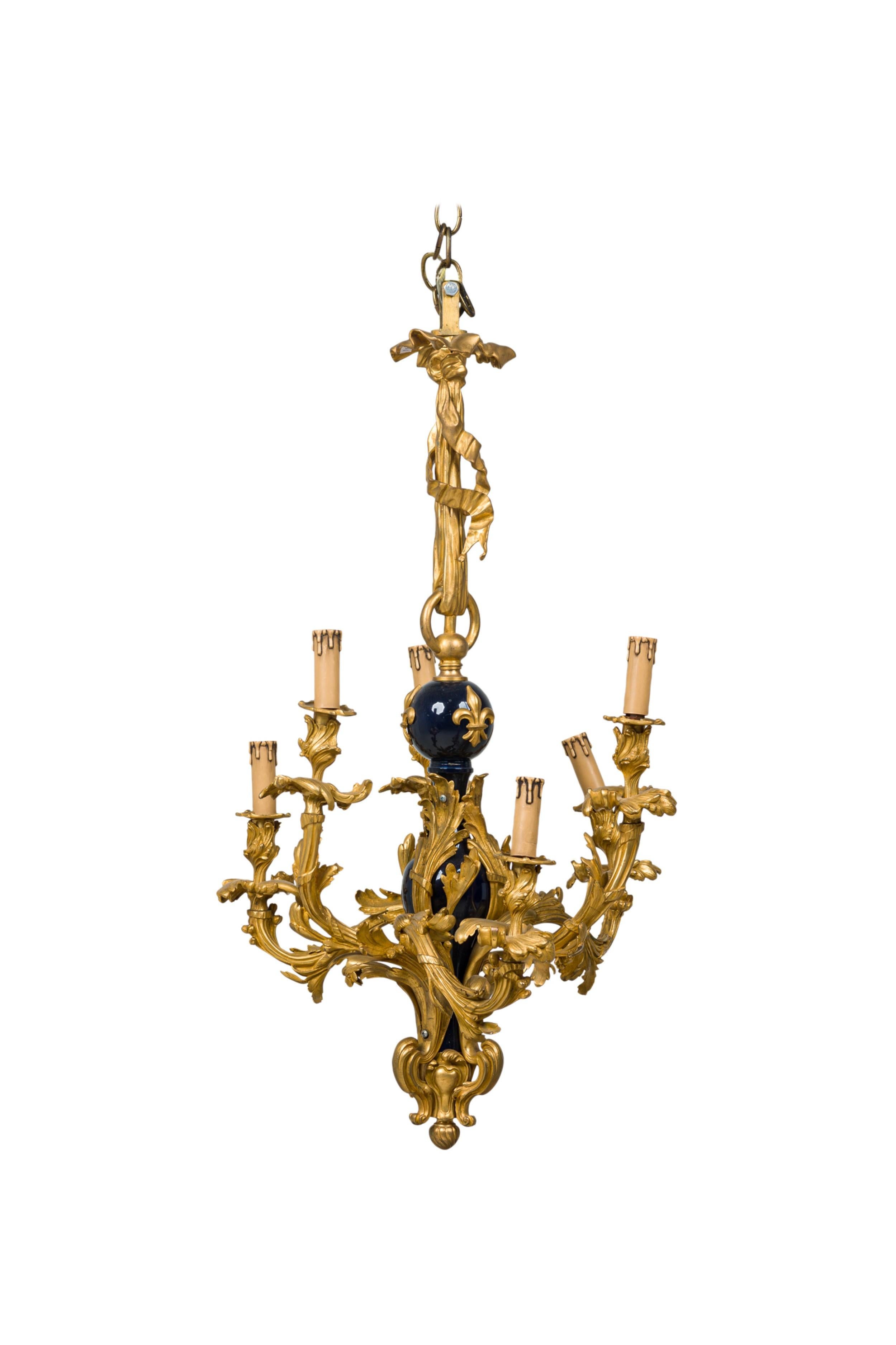 French Louis XV-Style (19th Century) bronze dore 8-arm chandelier featuring a Baroque scroll form frame and sculptural cobalt porcelain body with 3 applied bronze fleur de lis decorations at center.
