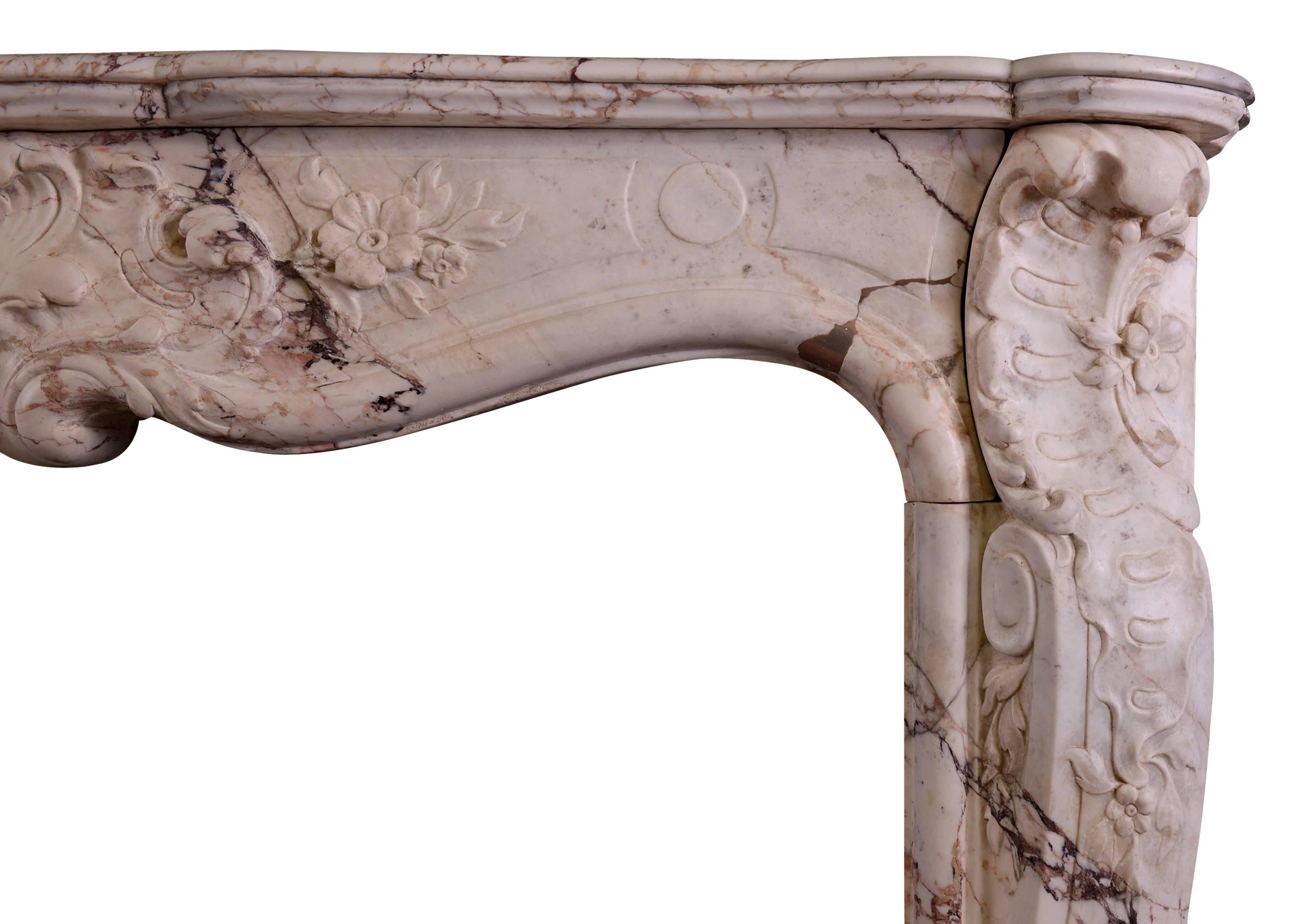 An 18th century Louis XV fireplace in a variegated Breche marble. The sweeping jambs with turned over leaf carving to tops and bases, the frieze with carved center of flowers and foliage. Serpentine shaped shelf.

Measure: Shelf width 1518 mm 59 ¾
