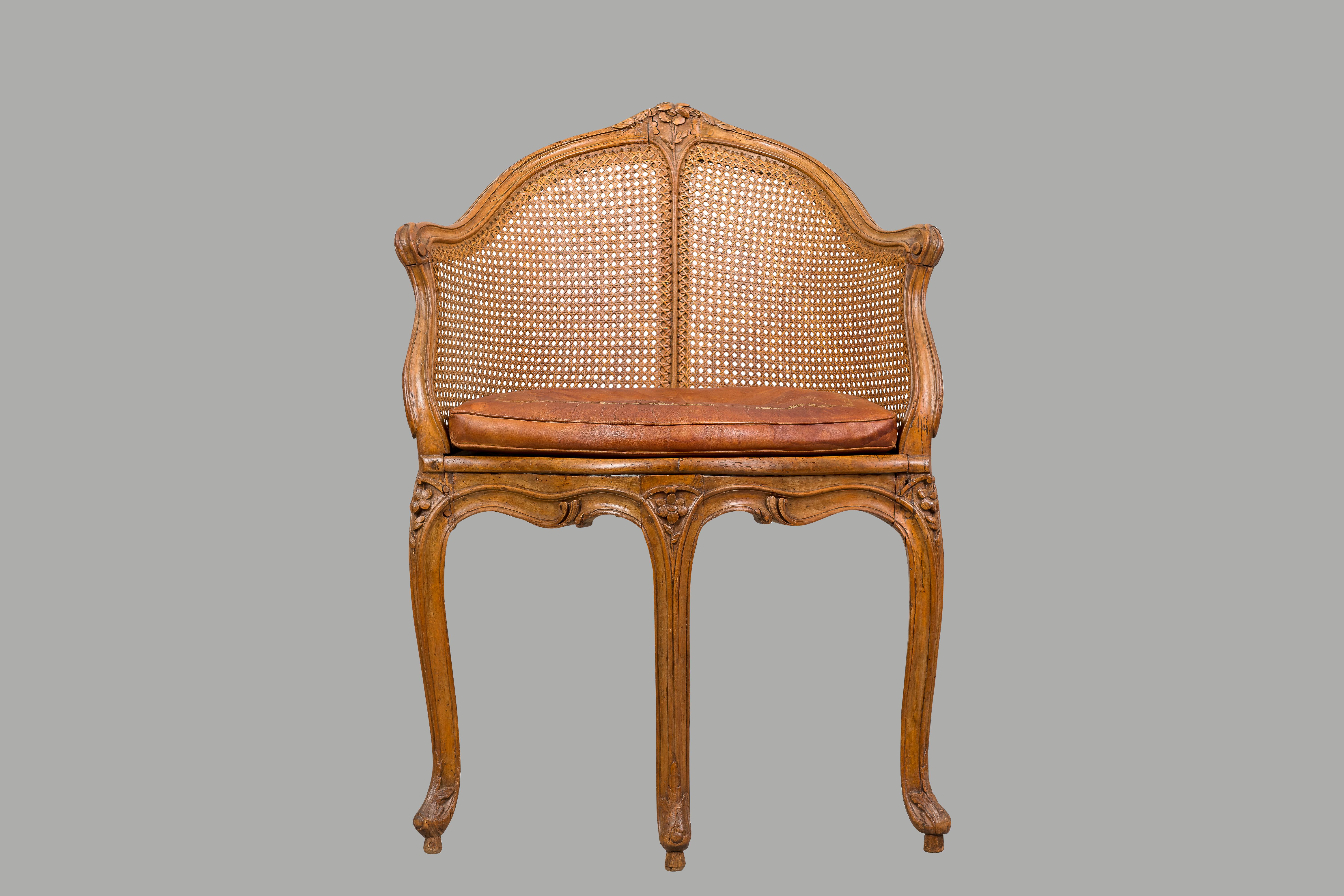 A Louis XV period beechwood and cane fauteuil de bureau, the curved crestrail with a carved central rosette terminating in molded downswept arms above a shaped seat resting on molded cabriole legs. Retains an antique tooled leather cushion, circa