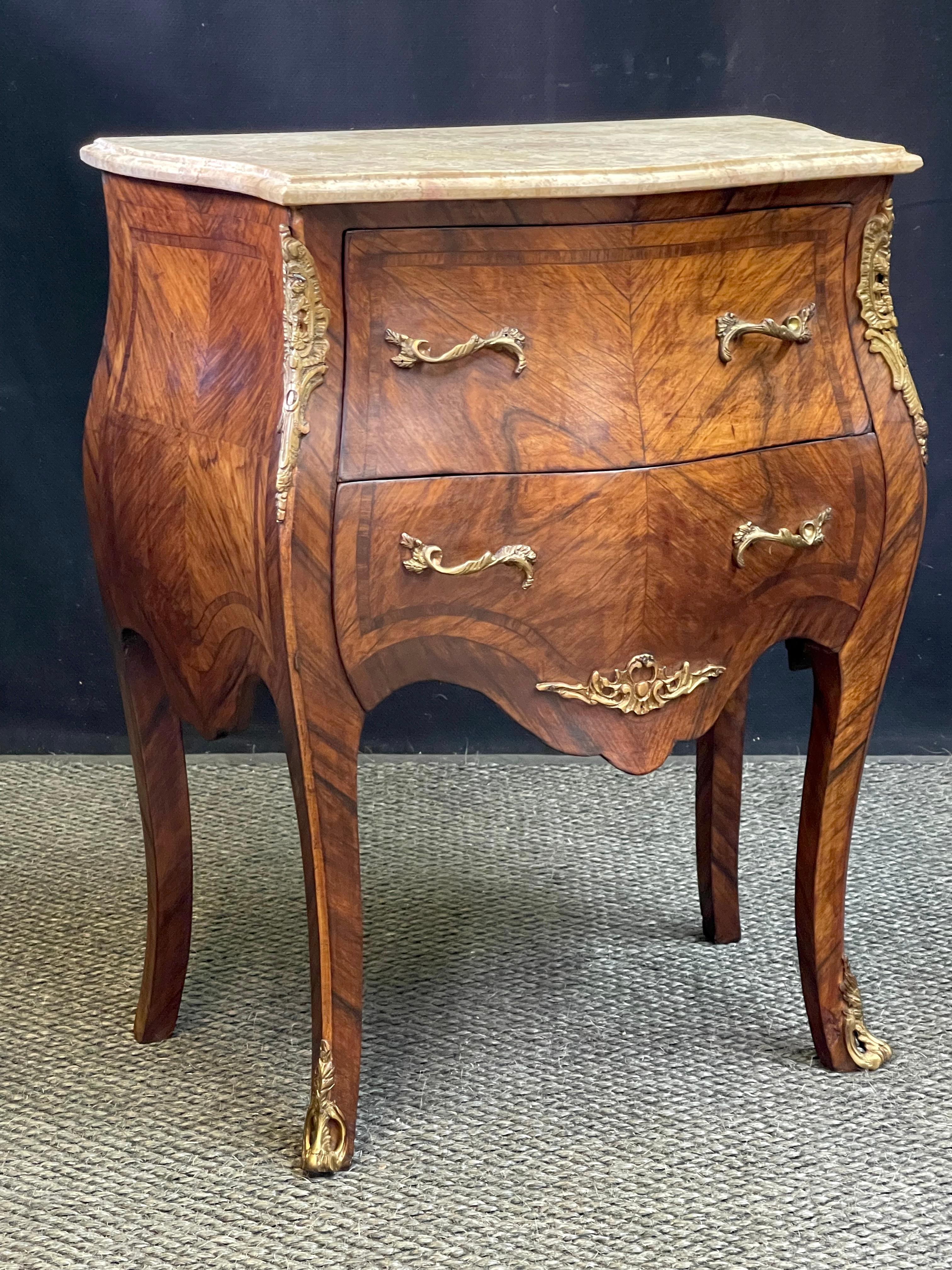A beautiful late 19th Century French bombe petite commode in the style of Louis XV, made with walnut butterfly veneer and rosewood inlay. A shaped marble top rests on a narrow case holding two drawers and having hardware and ornaments made of
