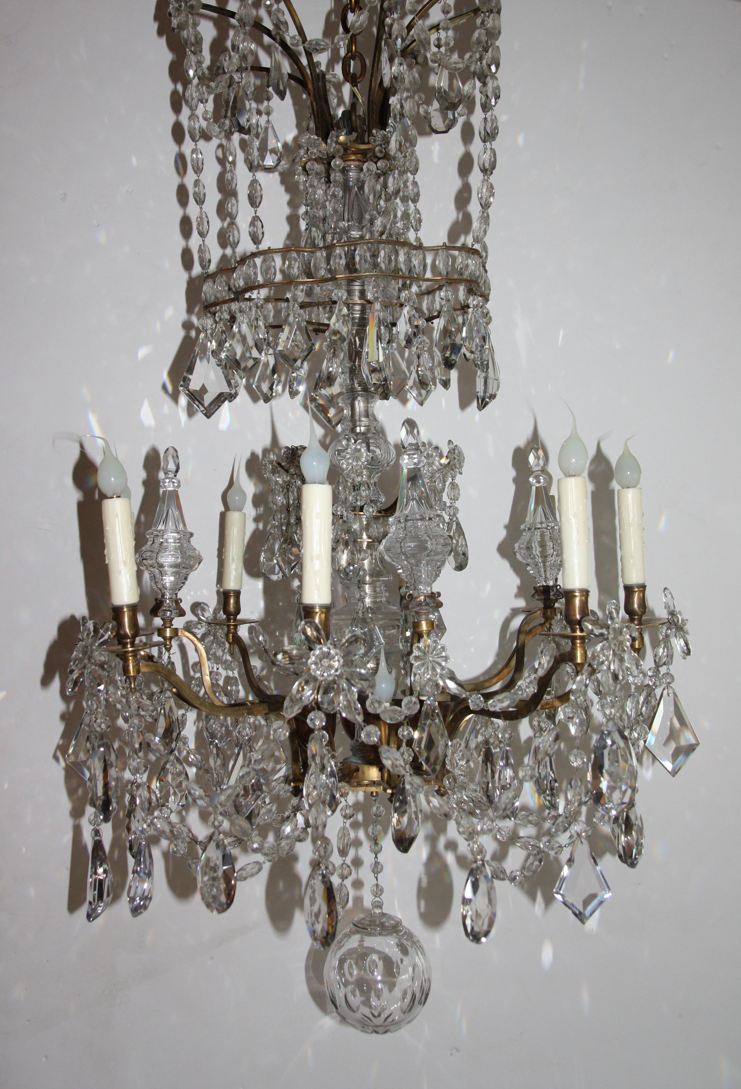 Monumental Louis XV chandelier in crystal and brass. Eight candle arms and 4 interior lights, prong-mounted crystal spires. Center rod encased in crystal. Assortment of clear cut prisms, crystal florets, strung crystal teardrops terminating in a