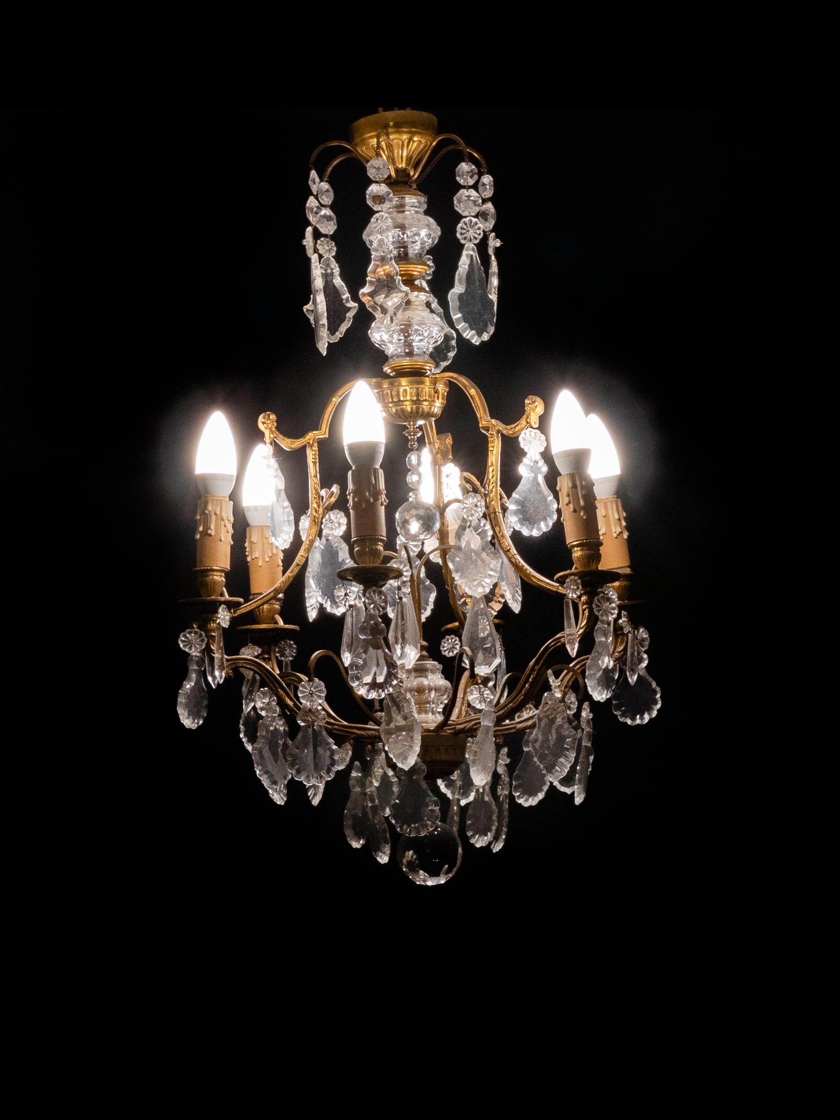 Uno splendido lampadario francese del XIX secolo in stile Luigi XV con bracci in bronzo, pendenti in cristallo e sei luci funzionanti. 

Realizzato in bronzo patinato con un dinamico effetto contorto, i suoi graziosi bracci sono ornati da pendenti e