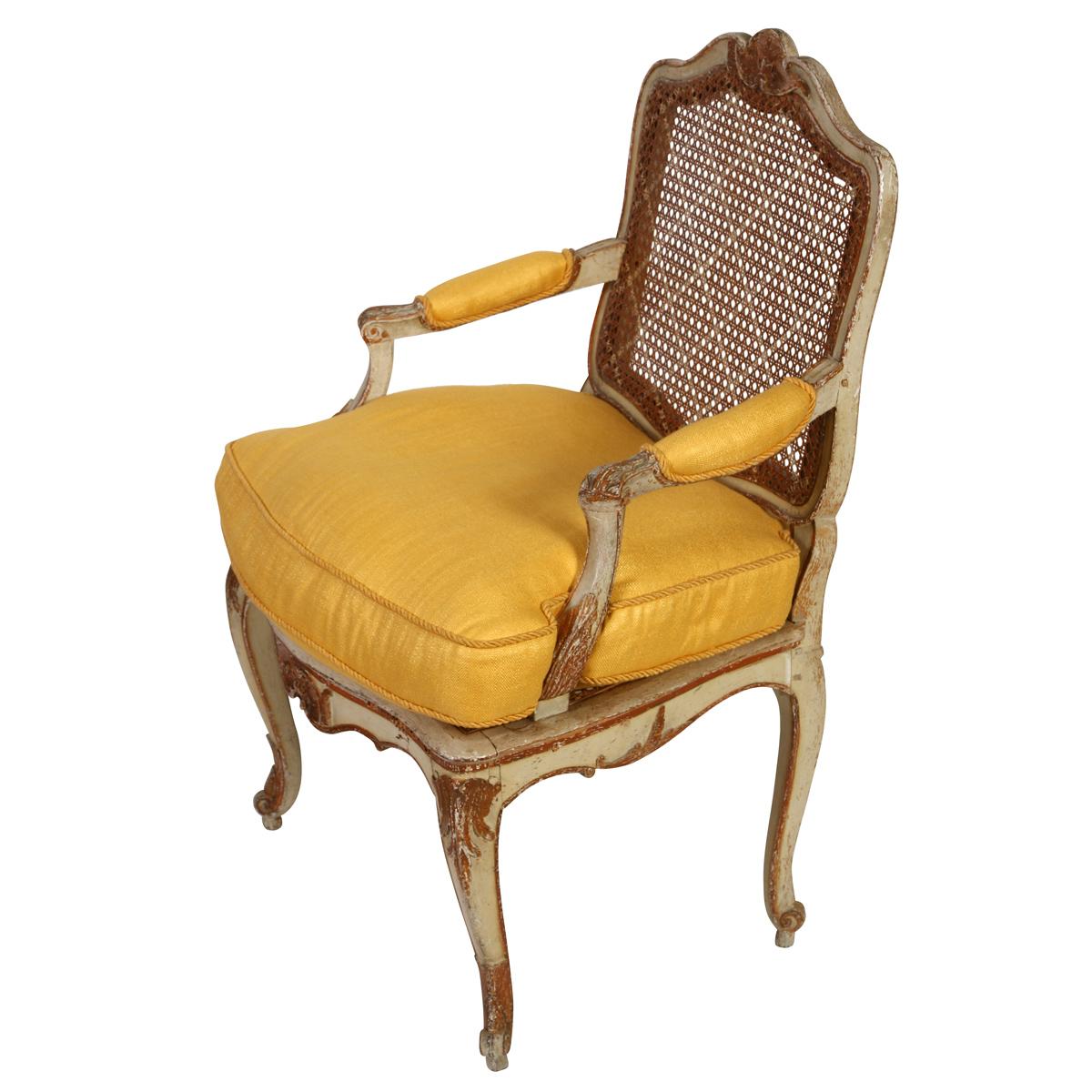 This elegant Louis XV style armchair features a finely crafted lattice design on the cane back, offering classic French charm and lightness. The seat cushion and armrests are newly upholstered and trimmed in a soft yellow linen, adding a fresh,