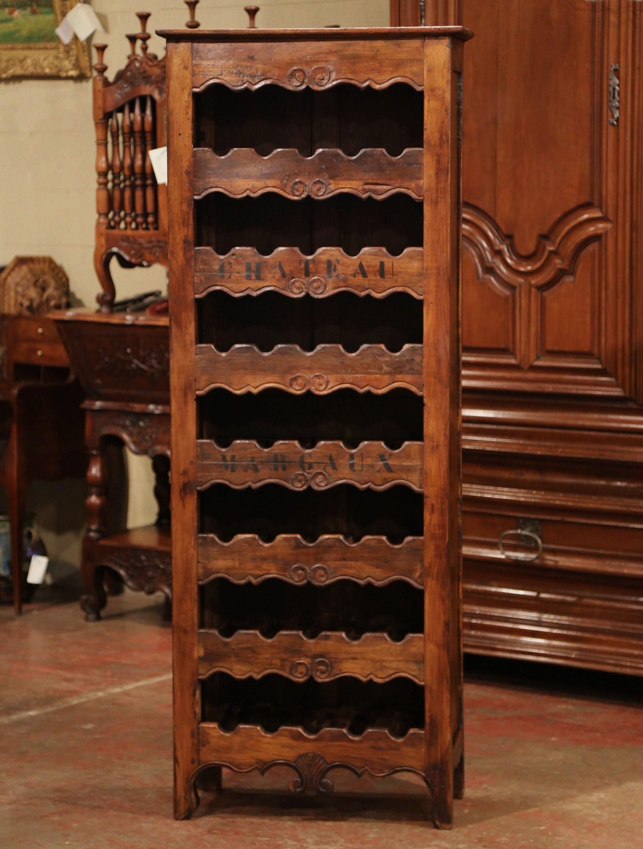 This elegant, antique wine storage cabinet was crafted in western France using old timber. The tall, simple pine cabinet sits on four small scroll feet under a scalloped apron. The useful, rustic storage cabinet features seven shelves with