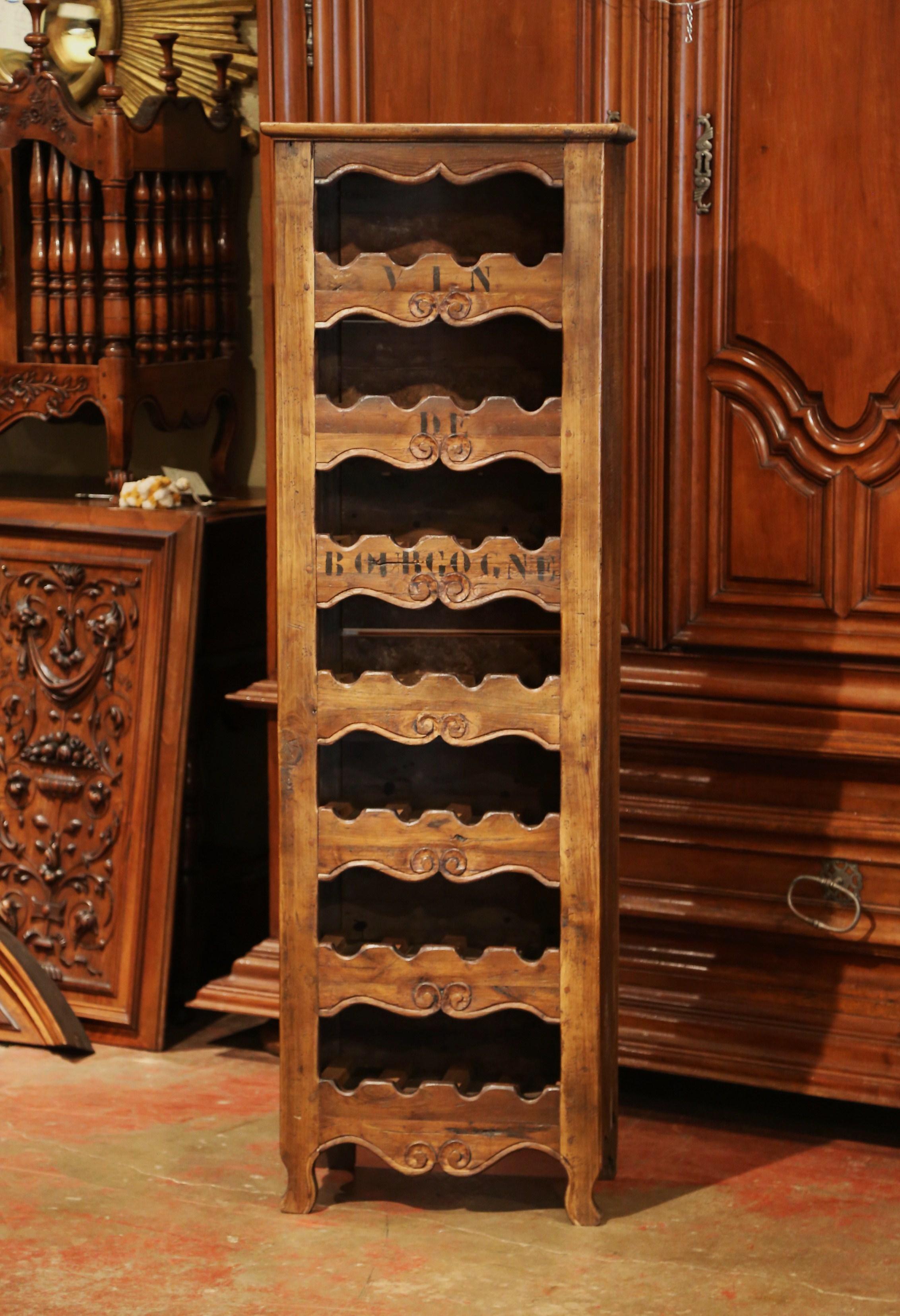 This elegant, antique wine storage cabinet was crafted in western France using old timber. The simple, tall, thin pine cabinet sits on four small scroll feet under a scalloped apron, and features seven shelves with decorative carvings. Each row
