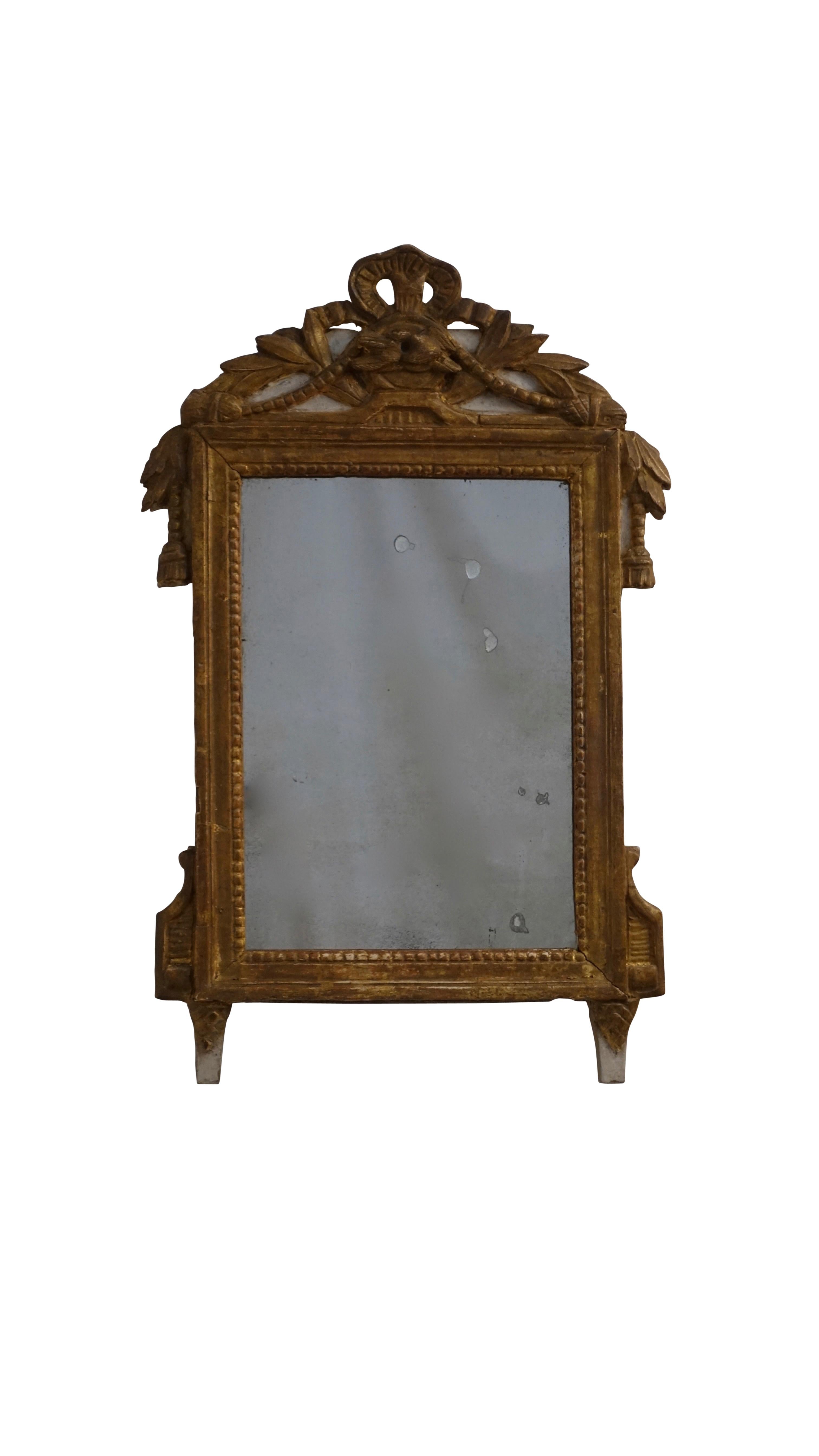 Louis XV hand carved and gilt boudoir mirror with parcel gray painting. Having a tied ribbon cartouche above a pair of love birds with tasseled cord and laurel leaves. Original mirror shows expected clouding and age. France, mid 18th century.