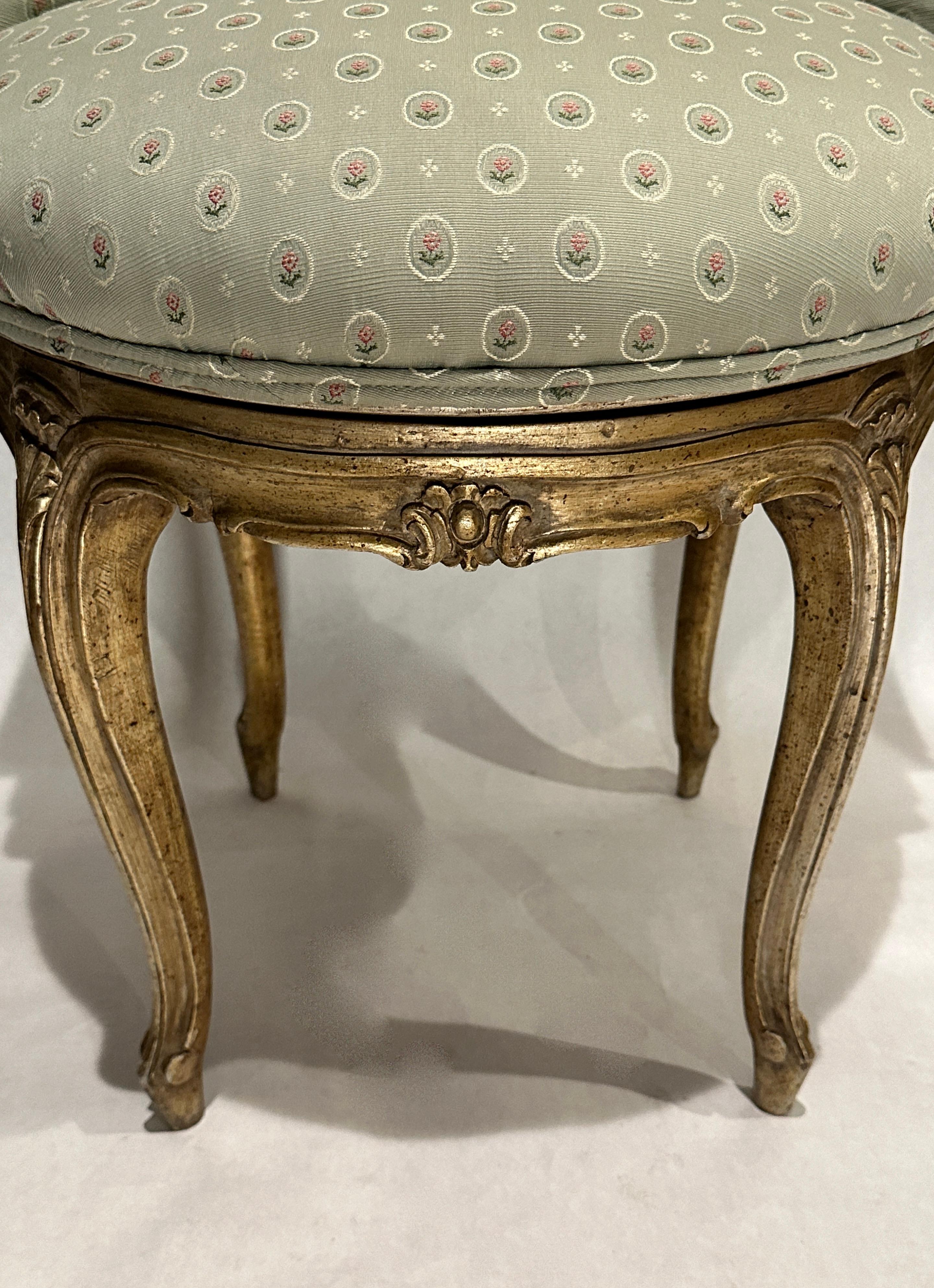 Drehstuhl im Stil Louis XV aus geschnitztem Holz und Silbervergoldung. Silberne Vergoldung mit dunkleren, antiken Schattierungen. Die Rückenlehne des Stuhls ist seitlich geschwungen und bildet flache Armlehnen.
