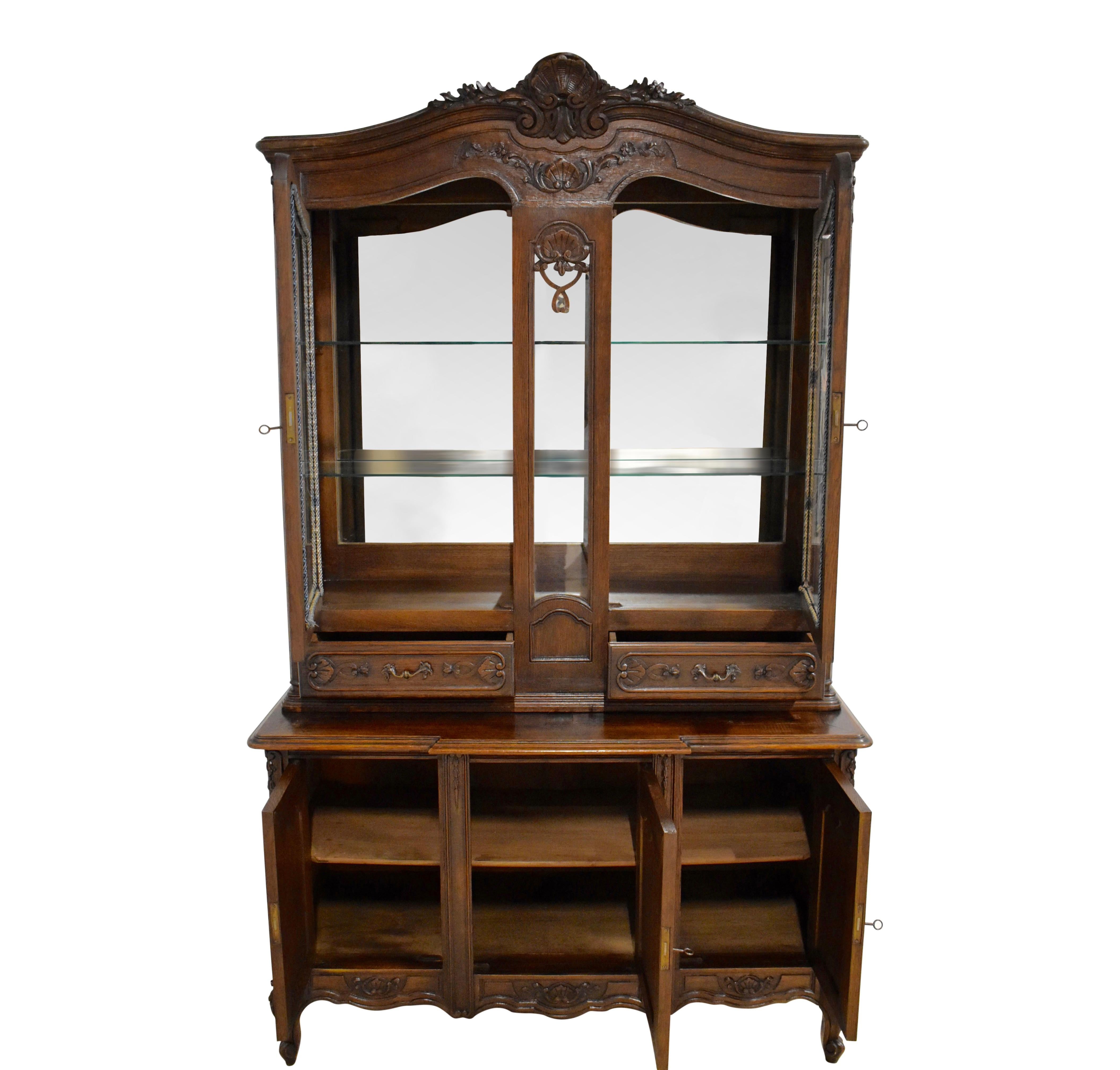 Generous storage and a delightful display case are paired in this remarkable Louis XV vitrine hutch. Crafted from beautiful European oak at the beginning of the twentieth century, the hutch is carved with shells, flowers, and scrolled acanthus