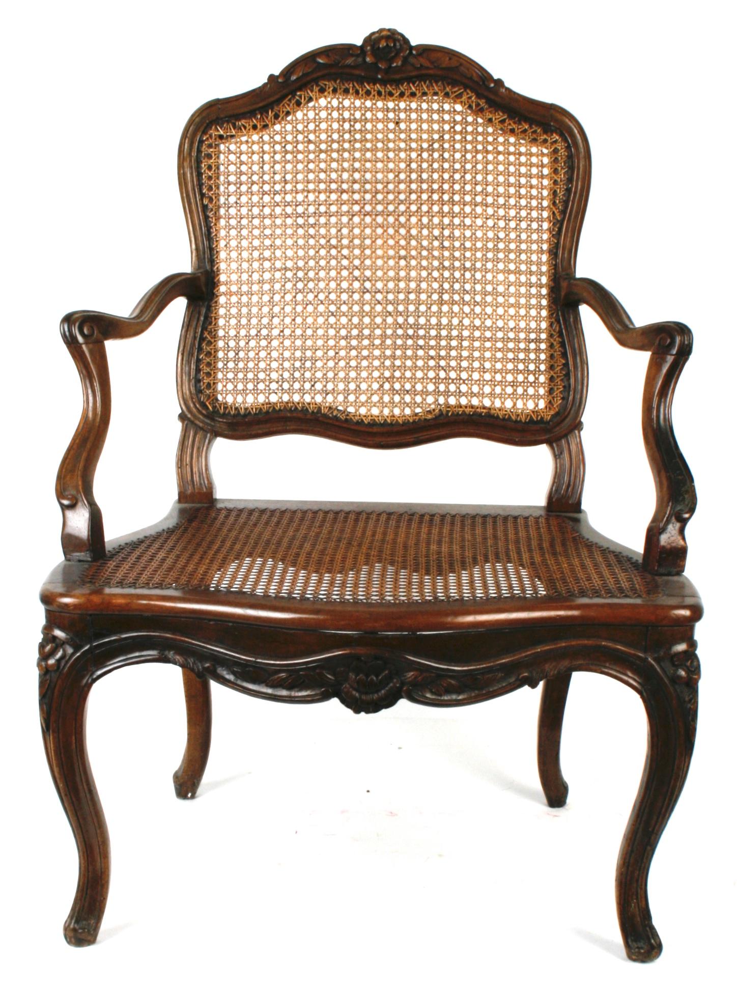 An early 18th century French carved walnut armchair with hand-caned seat and back. The frame is constructed in the customary 18th c Louis XV manner with pinned mortise and tenon and is carved with a scrolled floral design and raised on cabriole legs