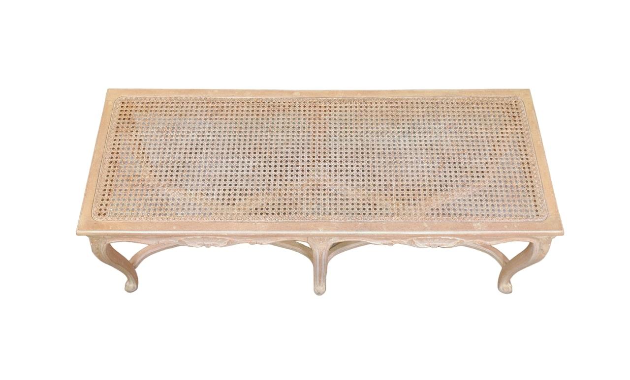 French Provincial Louis XV Style hand-crafted carved wood and cane bench. The natural wood frame is hand-carved and features shell details and 6 cabriole legs joined by shaped stretchers. The long seat is caned for light weight and is ideal for warm