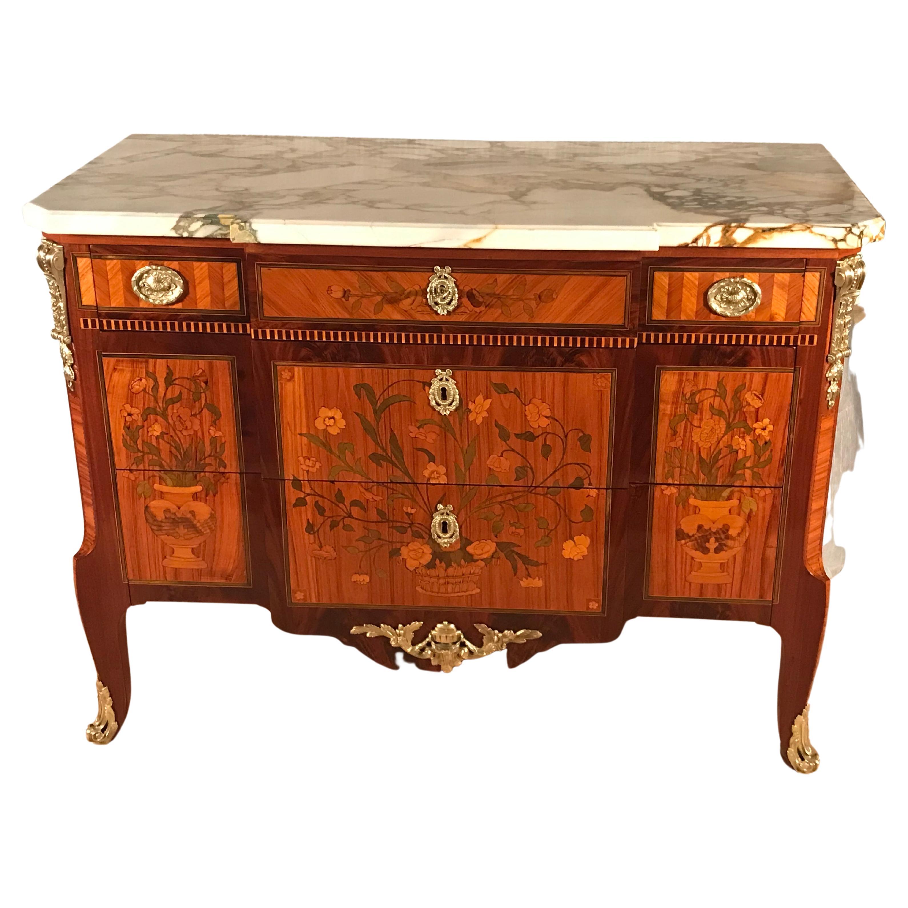 This gorgeous Louis XV Transition Style chest of drawers was made in the mid 19th Century.
The chest has an extraordinary flower marquetry. The three drawer commode's front is structured in different marquetry fields. The upper drawer has a middle