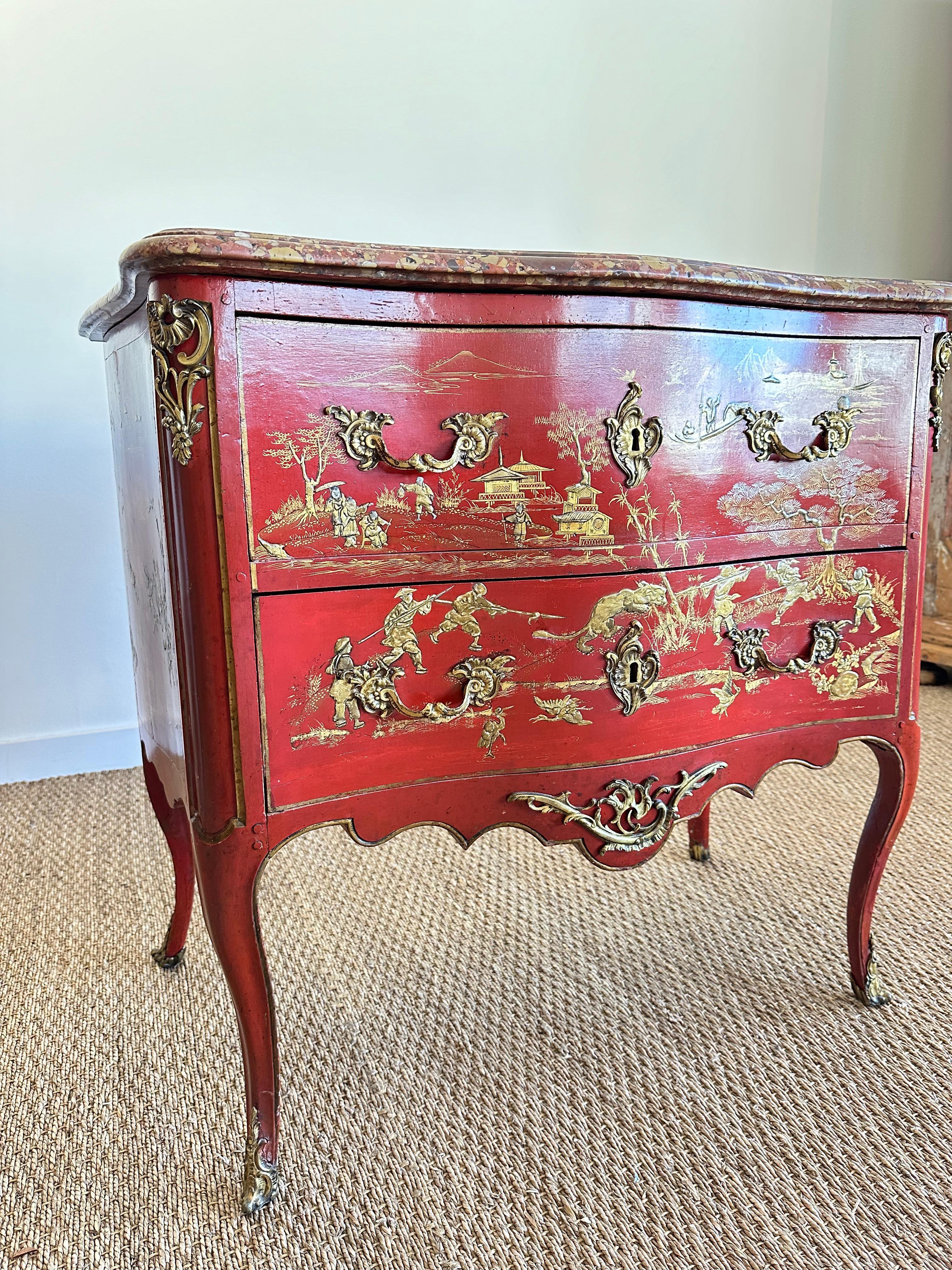 A Small period Louis XVI two-drawer commode red lacquer with gold Chinoiserie decoration, gilt bronze mounts, elegant pulls, beautiful keyhole escutcheons, and having a shaped conforming marble top, on tapered straight legs, by Parisian ébéniste