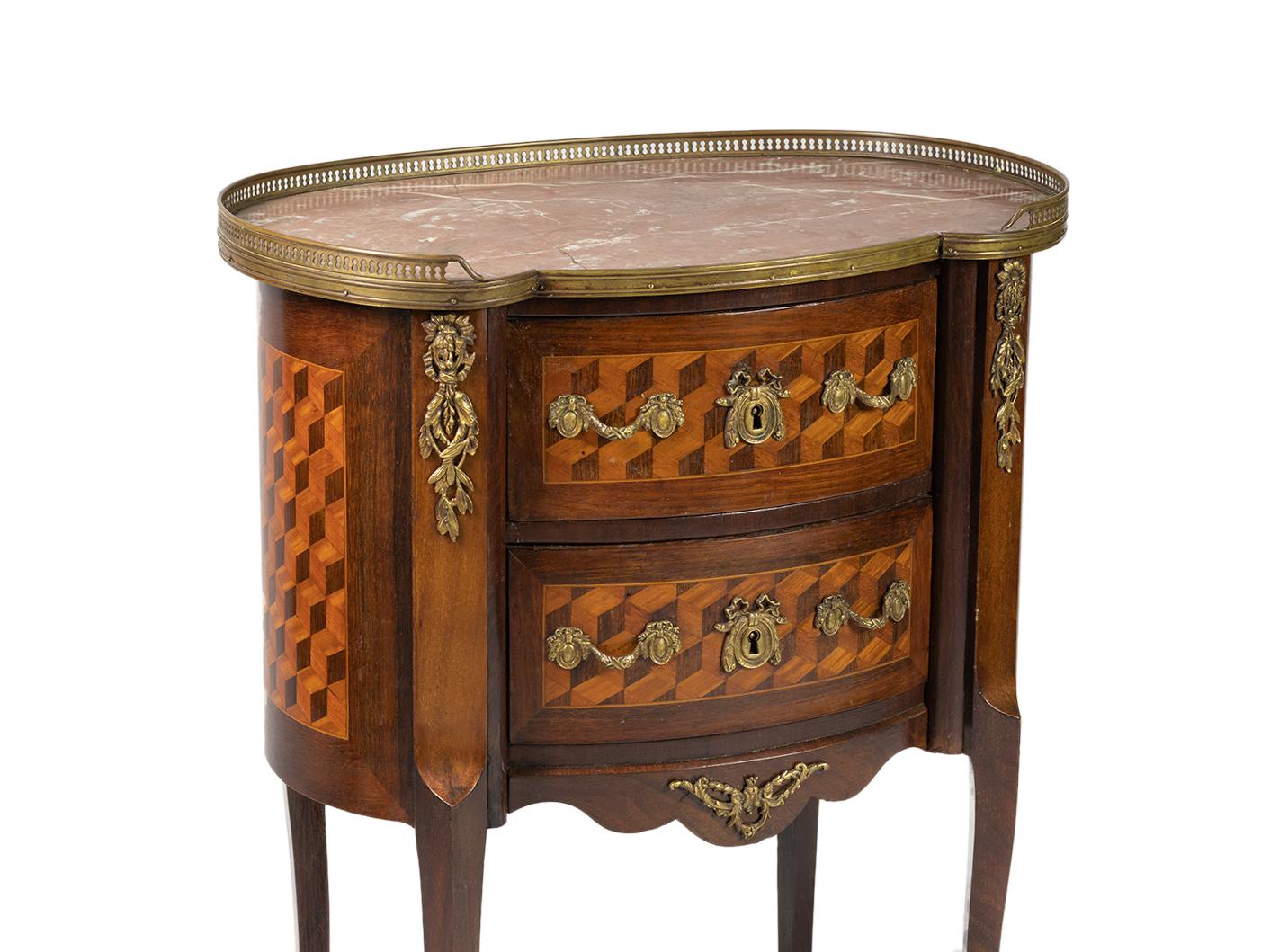 Una commode di forma ovale, un mobile da letto di transizione tra lo stile Luigi XV e Luigi XVI.
Tre cassetti, intarsi squisiti, ferramenta e fregi in bronzo dorato. 
Con ringhiere superiori in metallo e intarsi in marmo rosa Cedro proveniente dalle