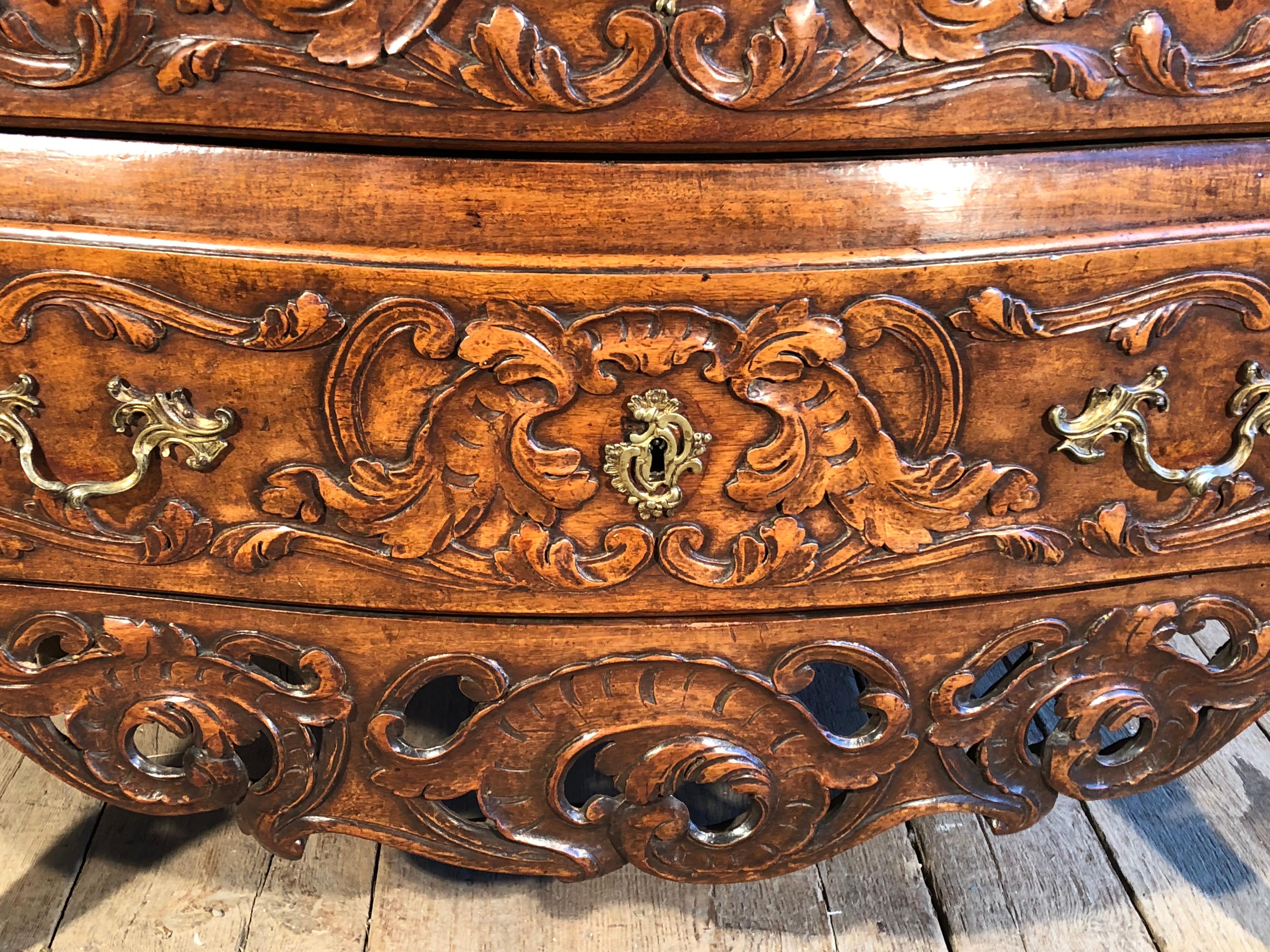 An important Louis XV period commode circa 1750 from Arles, in walnut, the case in a slight bombe form, with two drawers, ornately carved retaining its original brass drawer pulls. Commodes from this region and period are considered the pinnacle of