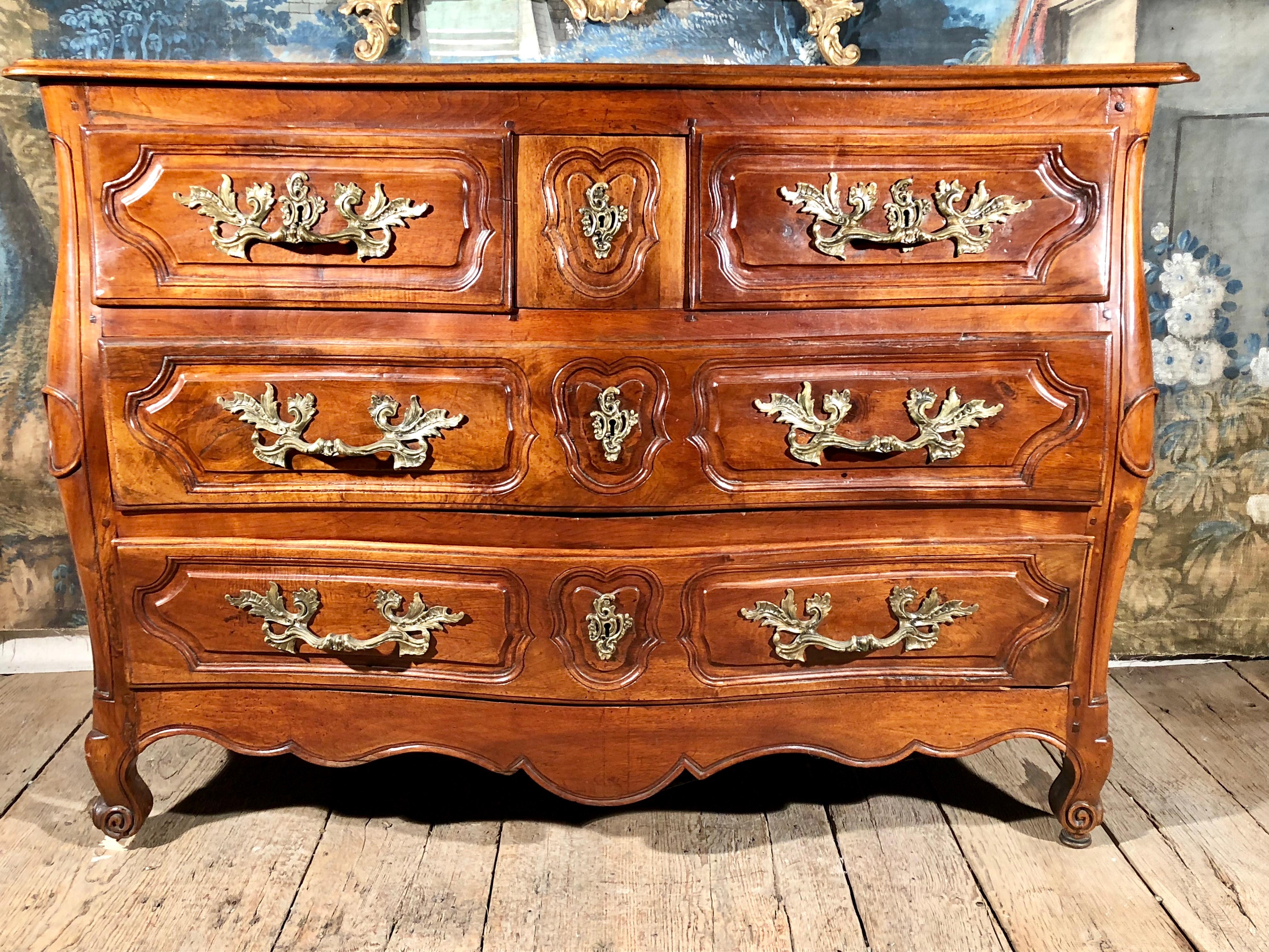 A fine Louis XV period walnut commode, the original conforming wood top over the serpentine form case with three small top drawers over two full length drawers, nicely carved and retaining its original gilt bronze hardware and working locks with