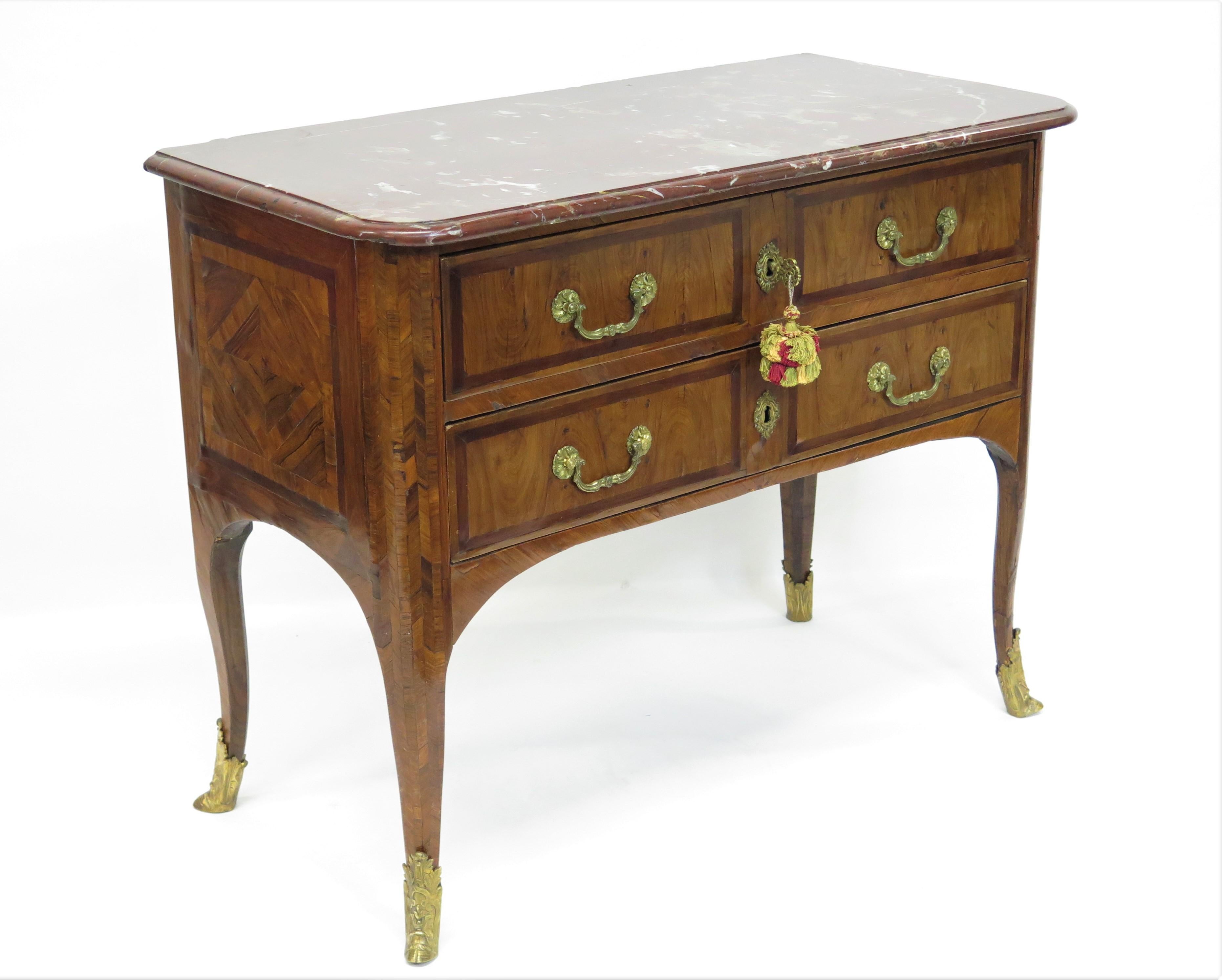 Louis XV two drawer commode with marquetry decoration, reddish marble top having grey and tan veining, shaped legs with gilt bronze sabots. with key, France, mid 18th century