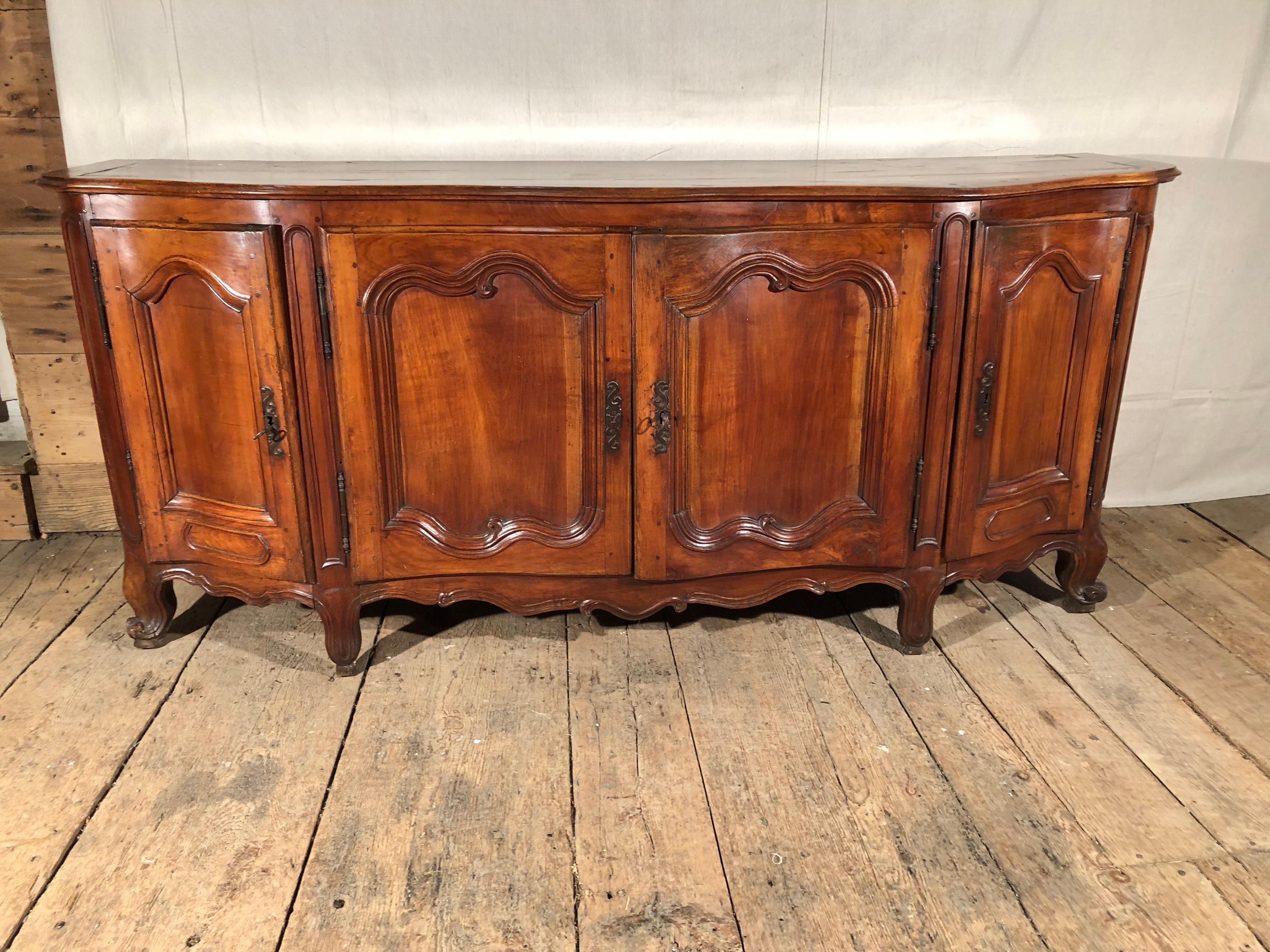 A fine quality Louis XV period enfilade buffet in fruitwood, circa 1760. Beautifully carved and constructed, with gracefully curved and paneled doors, scalloped apron and escargot feet, the piece retains its original iron hardware and wood top.