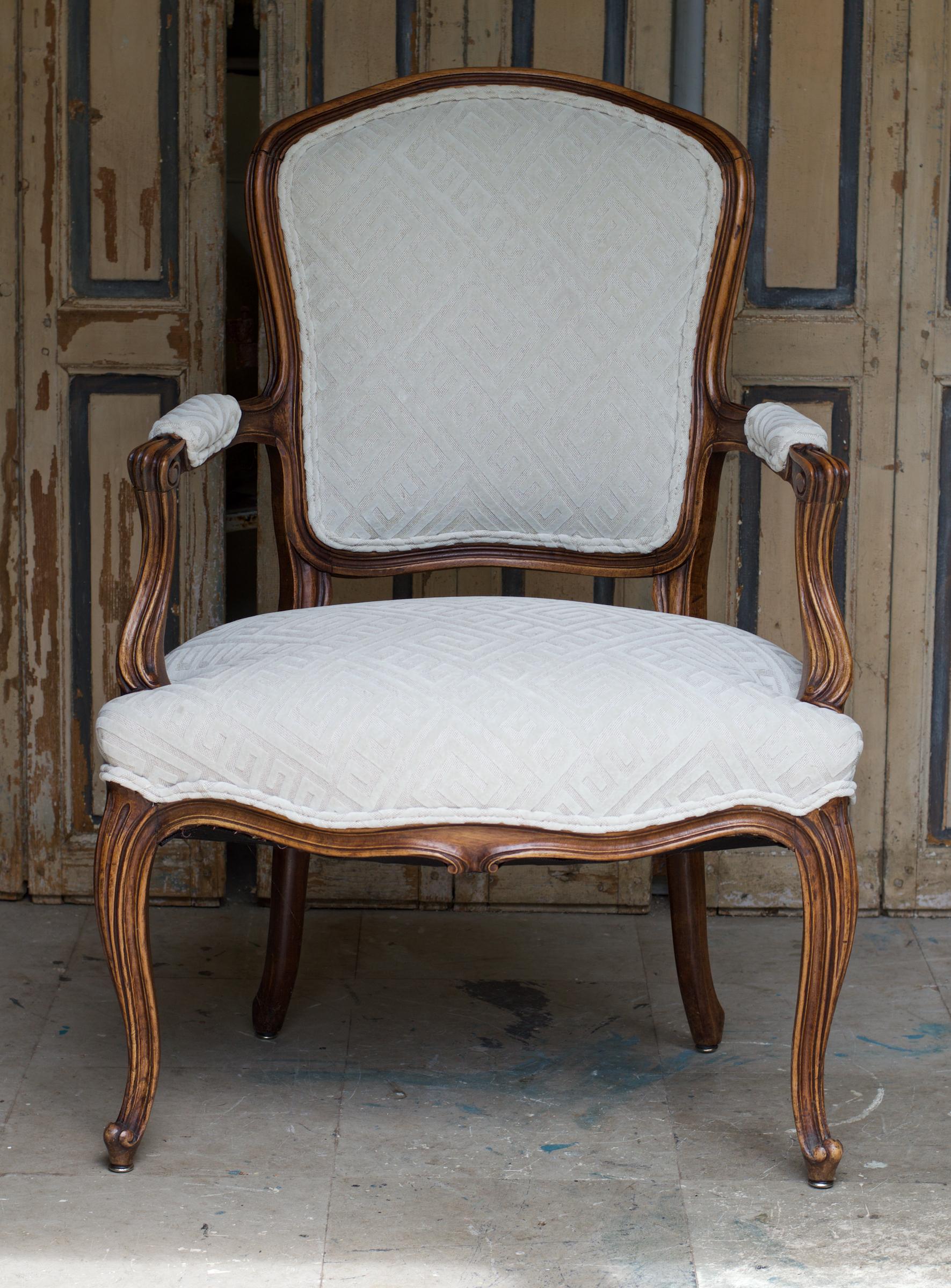 A glowing and chic Louis XV style fauteuil of carved fruitwood recently dressed in a neutral yet now, cut linen Greek key fabric. The look is Classic and sophisticated yet will allow for the 