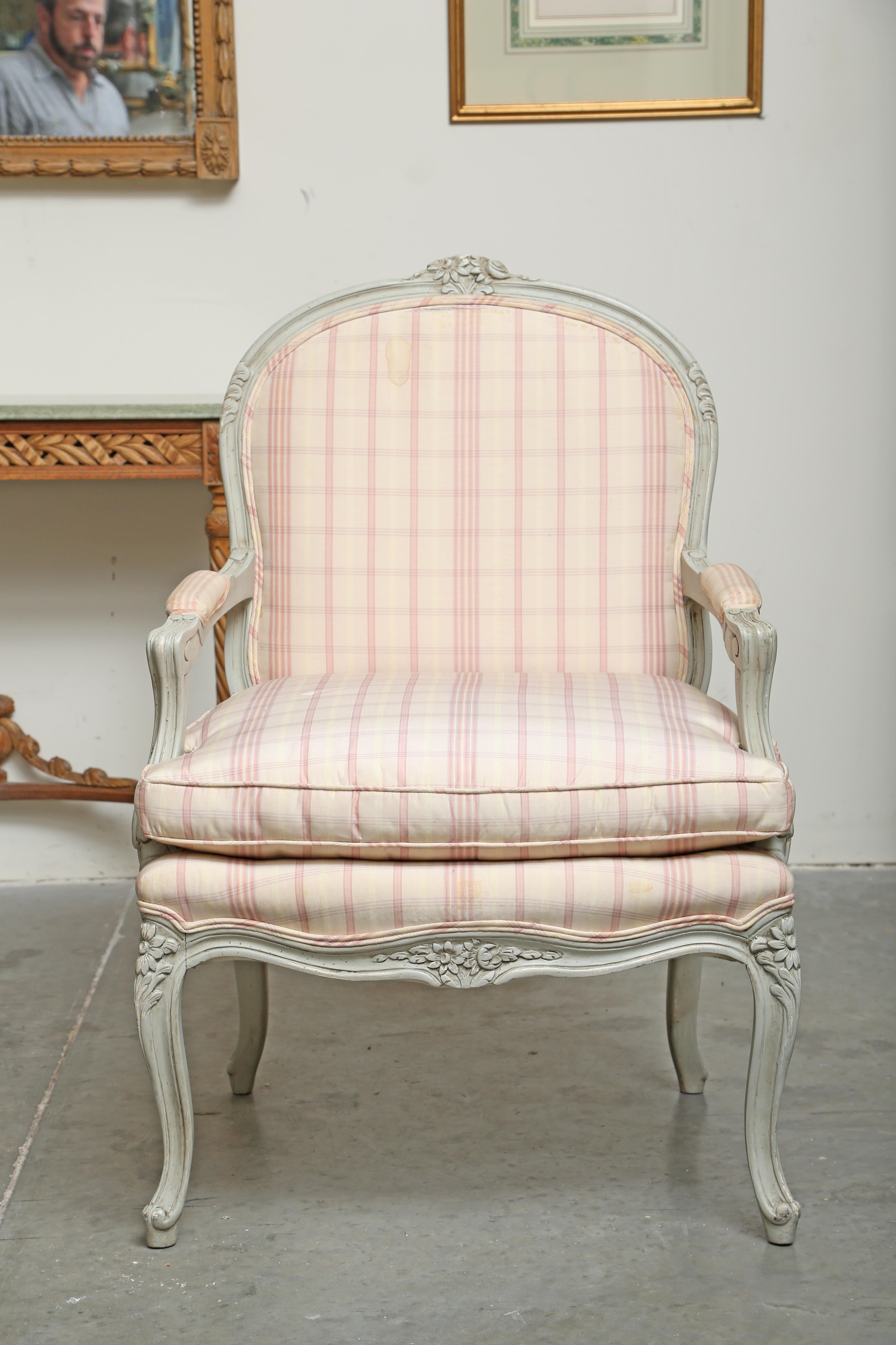 Louis XV style grey painted fauteuil marked Trouvailles on the underside. The crest rail, apron and knees are deeply hand-carved with marguerite daisy flowers. The Trouvailles Furniture Company was located in Watertown, Massachusetts. They were