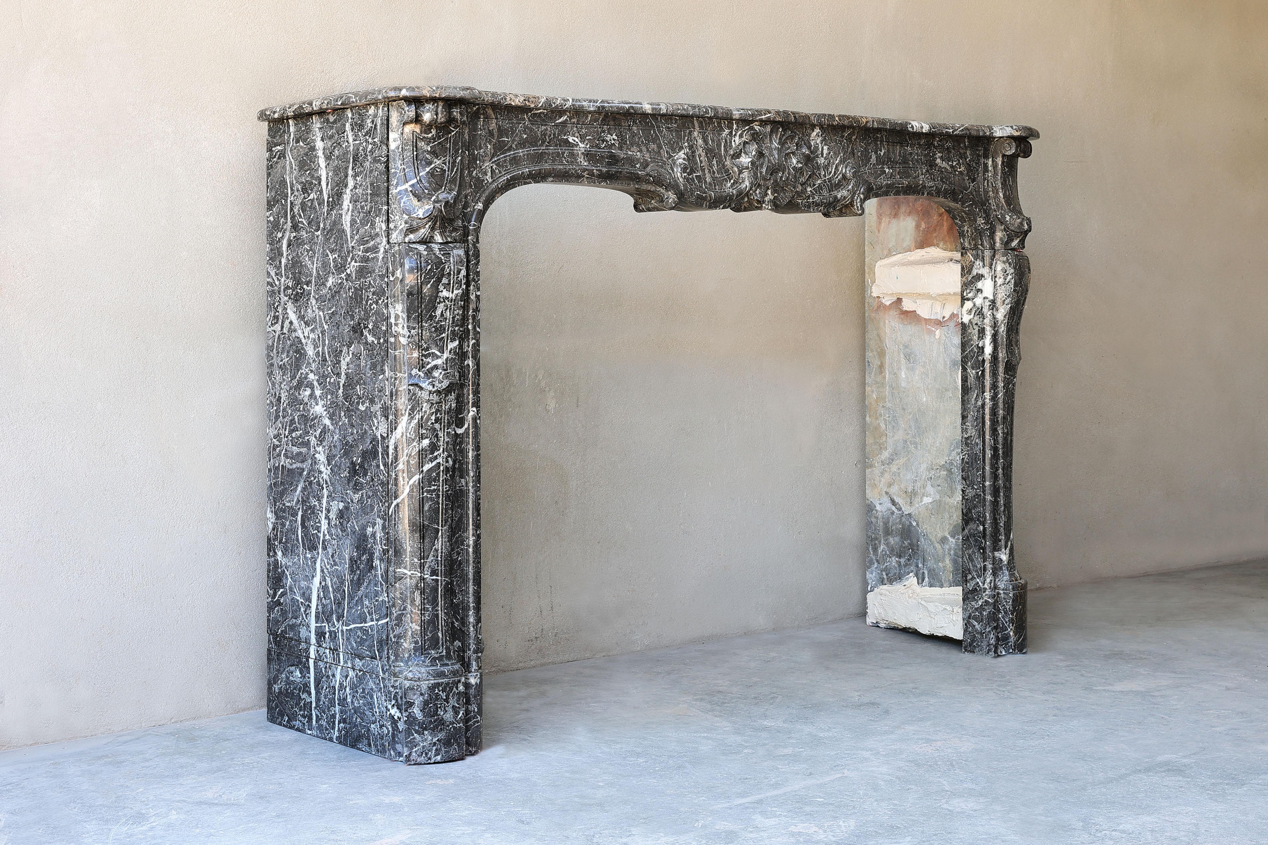 Beautiful chic antique fireplace of Saint Anna marble, a beautiful rustic kind of marble with light veins. This fireplace is in the style of Louis XV and dates from the 18th century. The beautiful veins and ornate ornaments make this fireplace