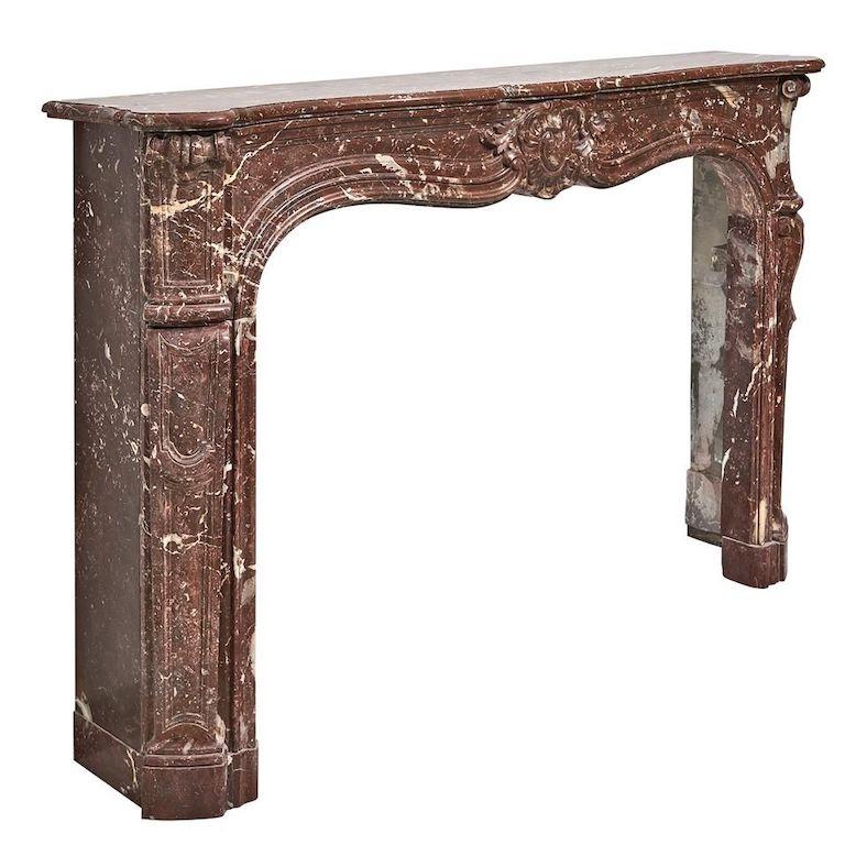 An impressive, Belgian Louis XV fireplace from the late 19th century.
The serpentine shelf is resting on the fine shaped frieze, which is centered by a shell cartouche,
flanked by scrolled endblocks. The tapering, angled and paneled console jambs