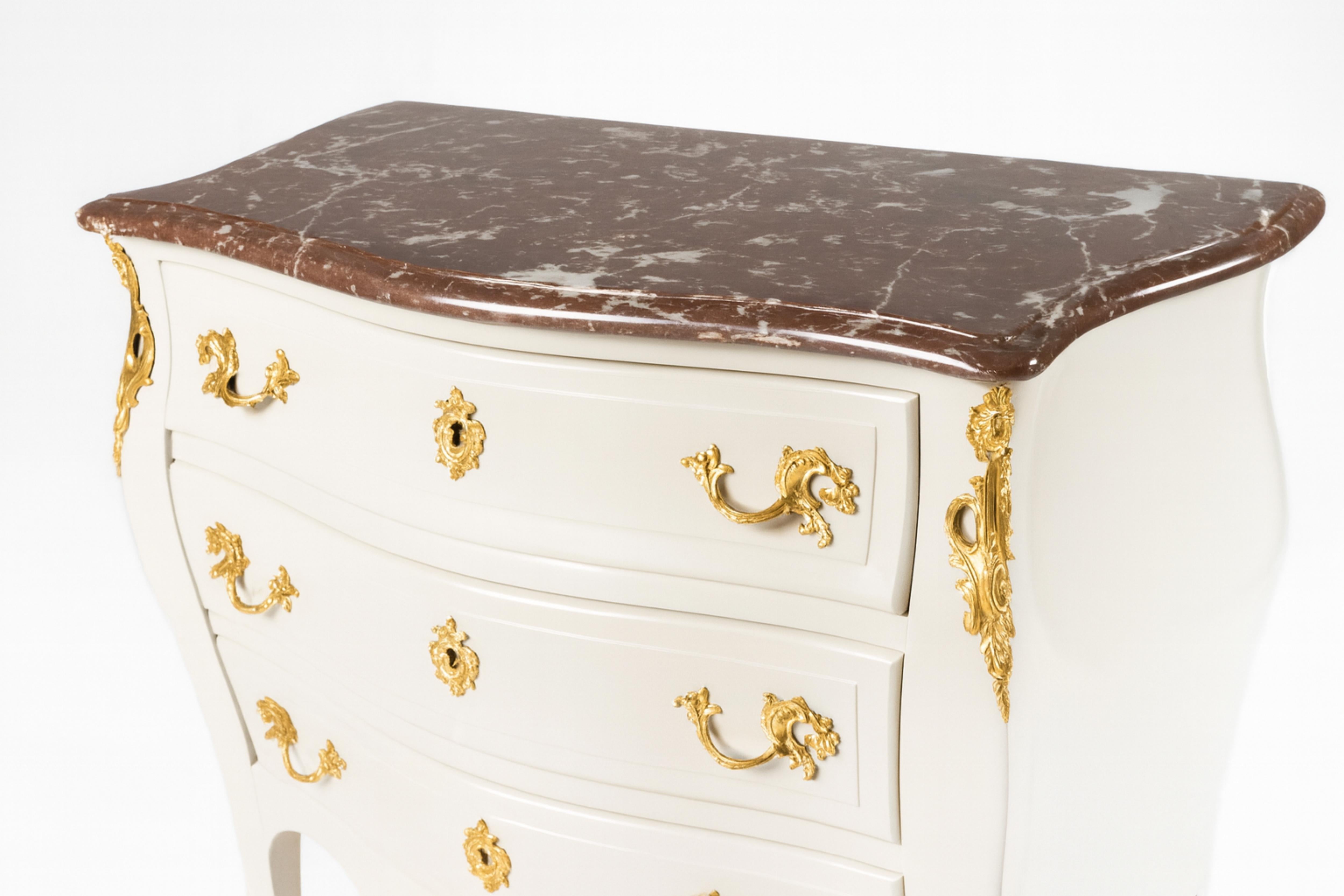 Commode en noyer, laquée blanc cassé, avec poignées en bronze doré et trois tiroirs. Le tiroir supérieur comporte trois tiroirs intérieurs. Il s'agit d'une pièce de François Hugnet, un artisan accompli de la rue Faubourg Saint-Antoine, à Paris.  