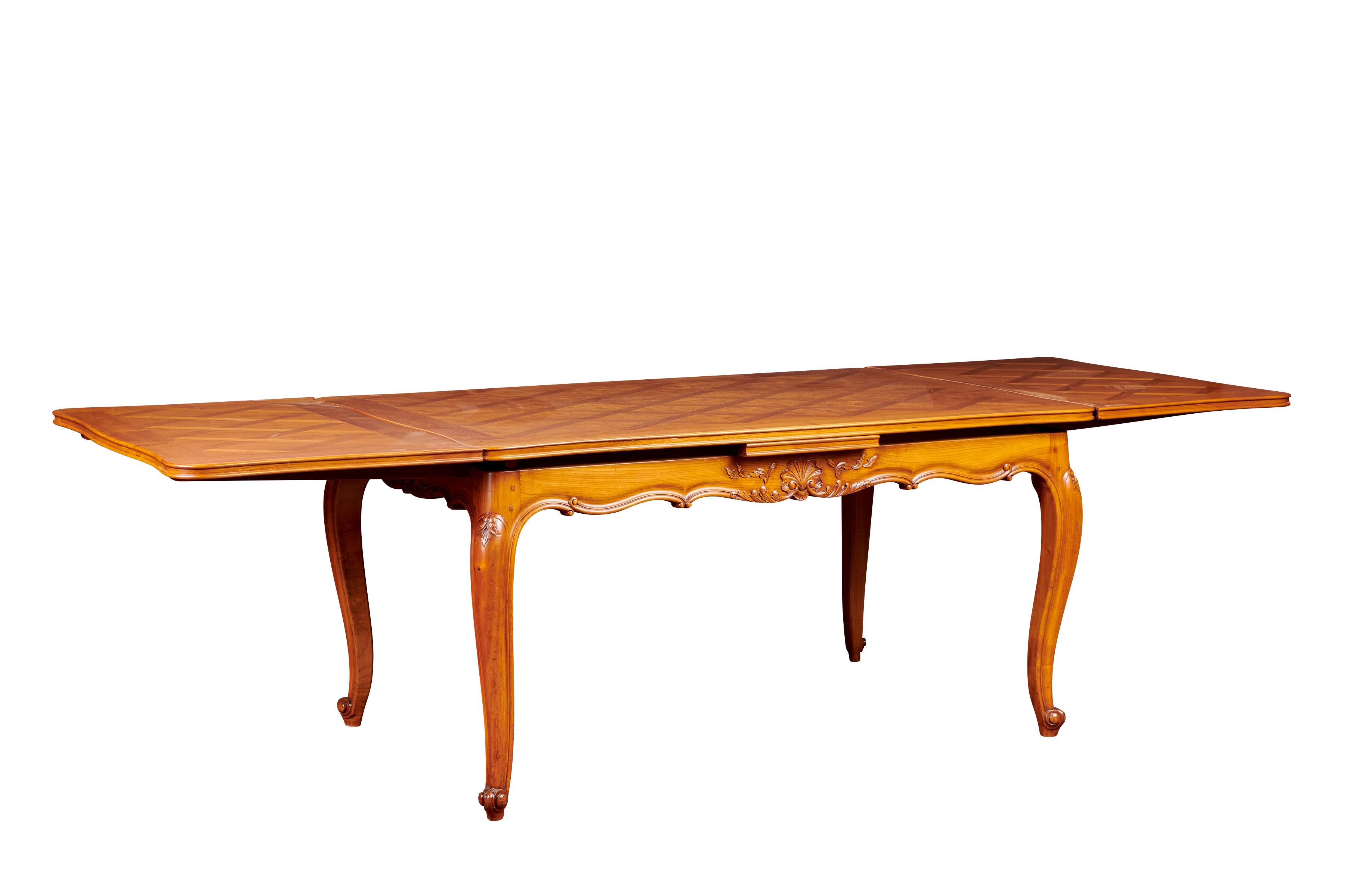 In true Louis XV style, this perfect extendable French dining table has been dated at mid-20th century and has been carved out of cherrywood. Featuring fleur carvings and adornments to the tables’ sides and cabriole legs, the top of this table