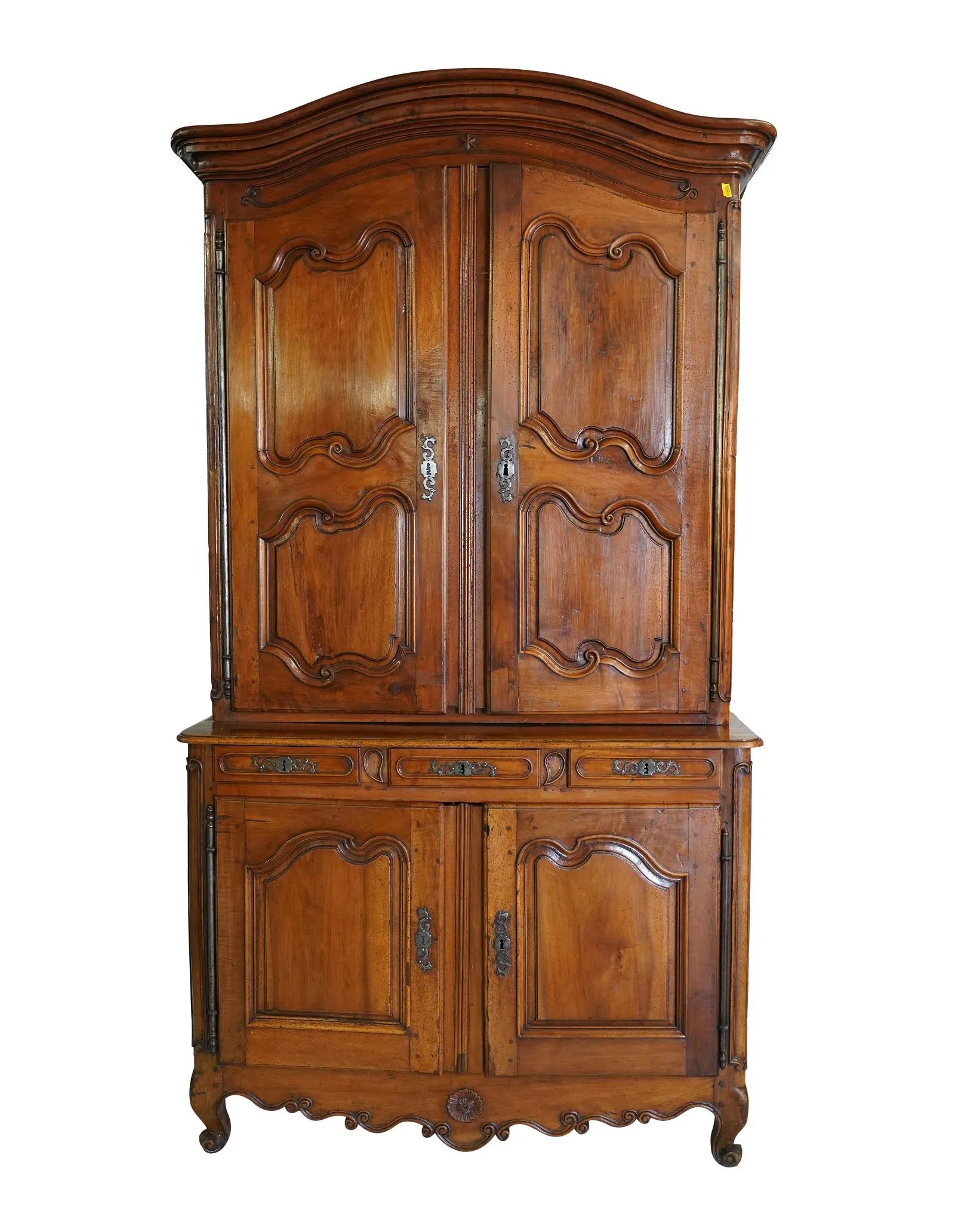 Monumental late 18th Century Louis XV Provincial Walnut Buffet a Deux Corps in two sections. The upper section with two carved paneled doors opening to a compartment with two shelves. The lower section with 3 drawers over a two door cabinet opening