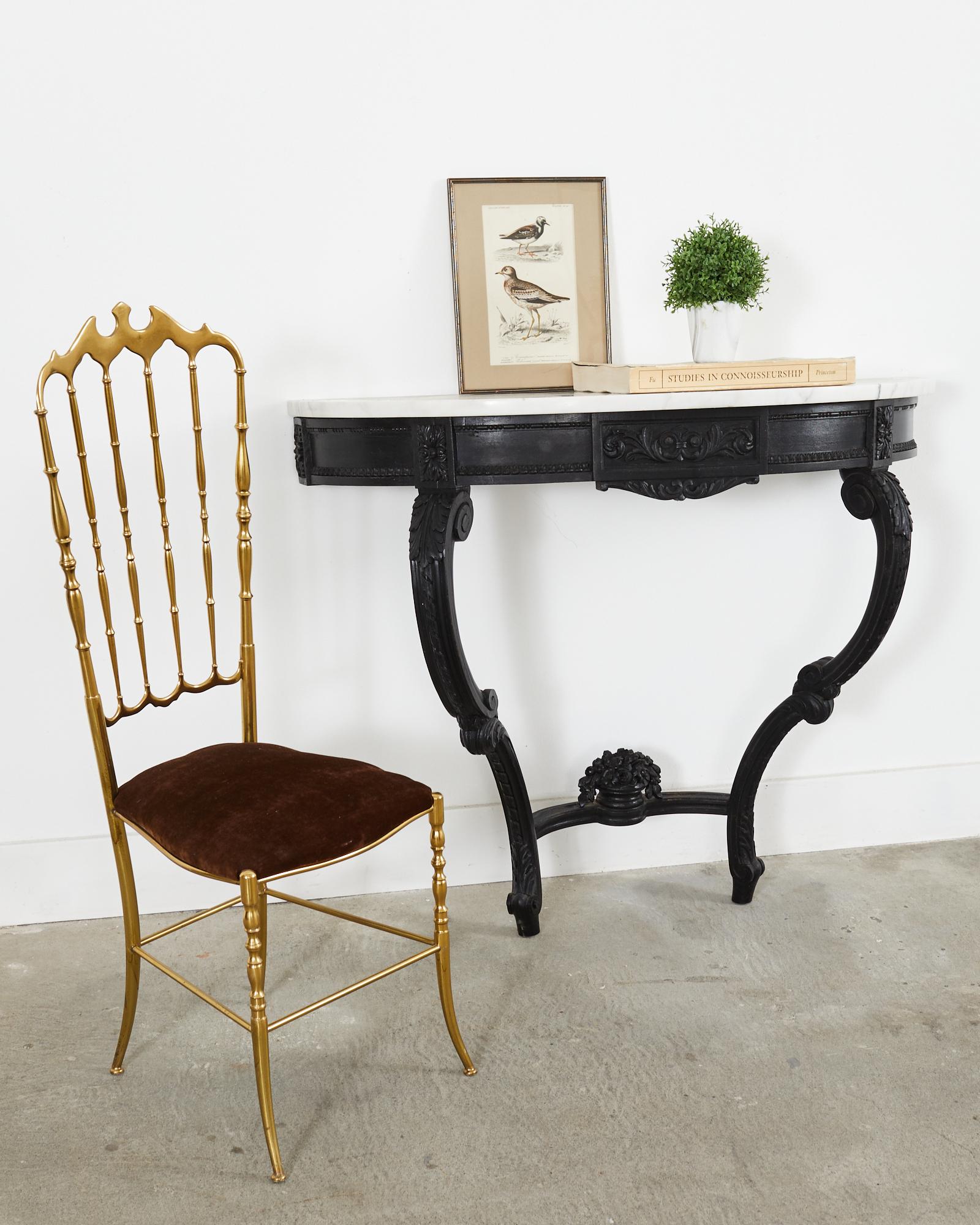 Dramatic black lacquered wall mounted demi-lune console table featuring a conforming Carrara marble top made in the grand French provincial or Louis XV taste with carved rosettes and acanthus decorated frieze. The table is supported by gracefully