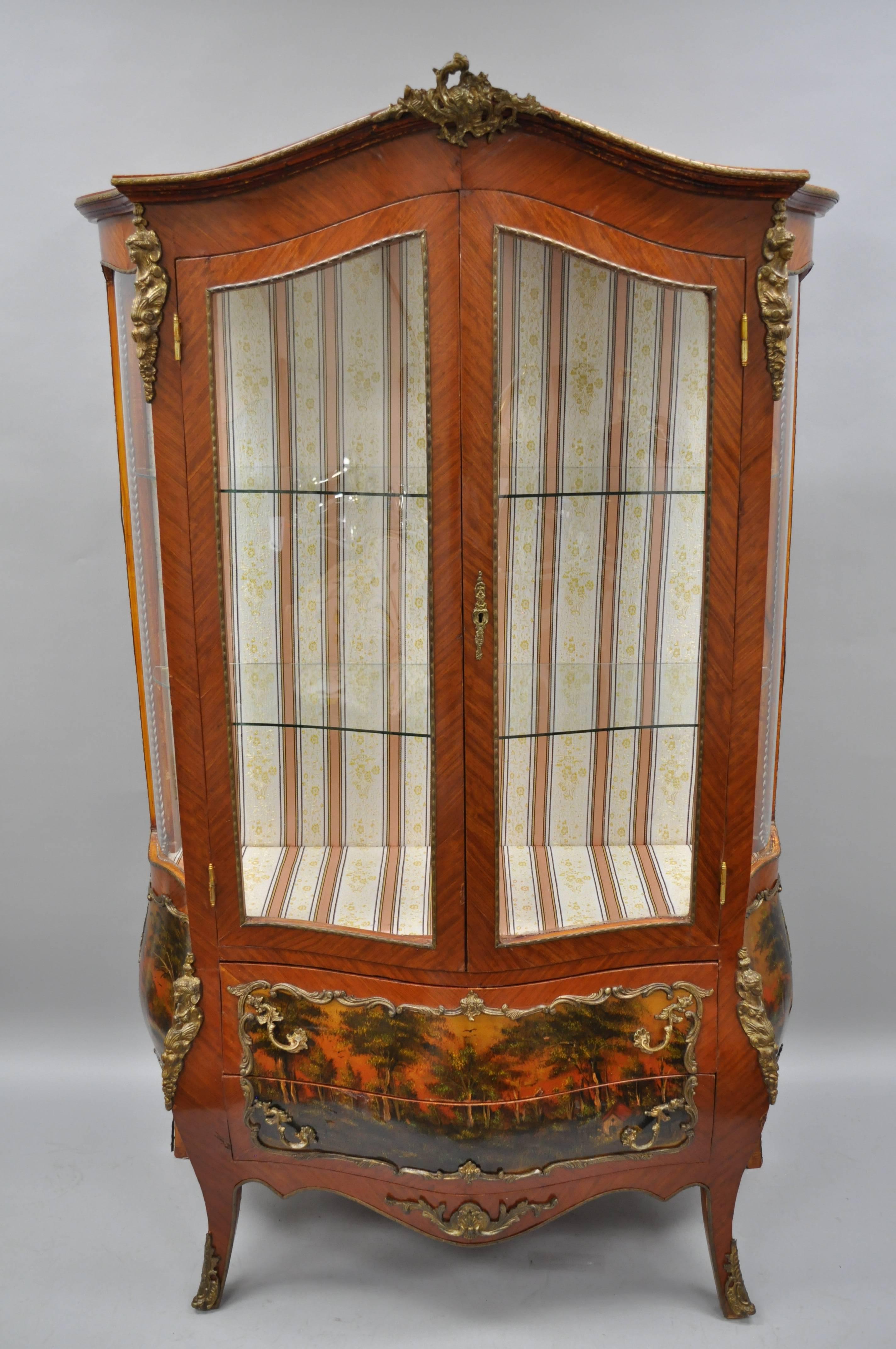 Louis XV French style reproduction bombe curio cabinet vitrine with bronze ormolu. Item features figural bronze ormolu, upholstered interior, bombe form, four curved glass exterior panels, painted scenes, two shaped glass shelves, great style and