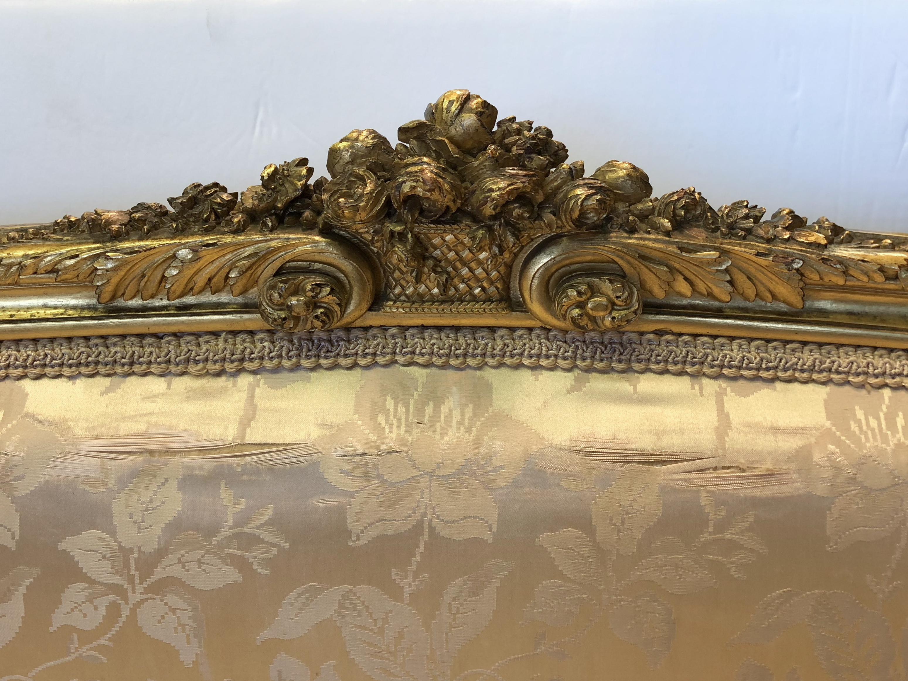 A 19th century Louis XV gilt carved mahogany loveseat with what appears to be original silk upholstery, horsehair stuffing and antique sprung seat. Beautifully carved mahogany frame, prime for reupholstery; some wear to gilding and frame consistent