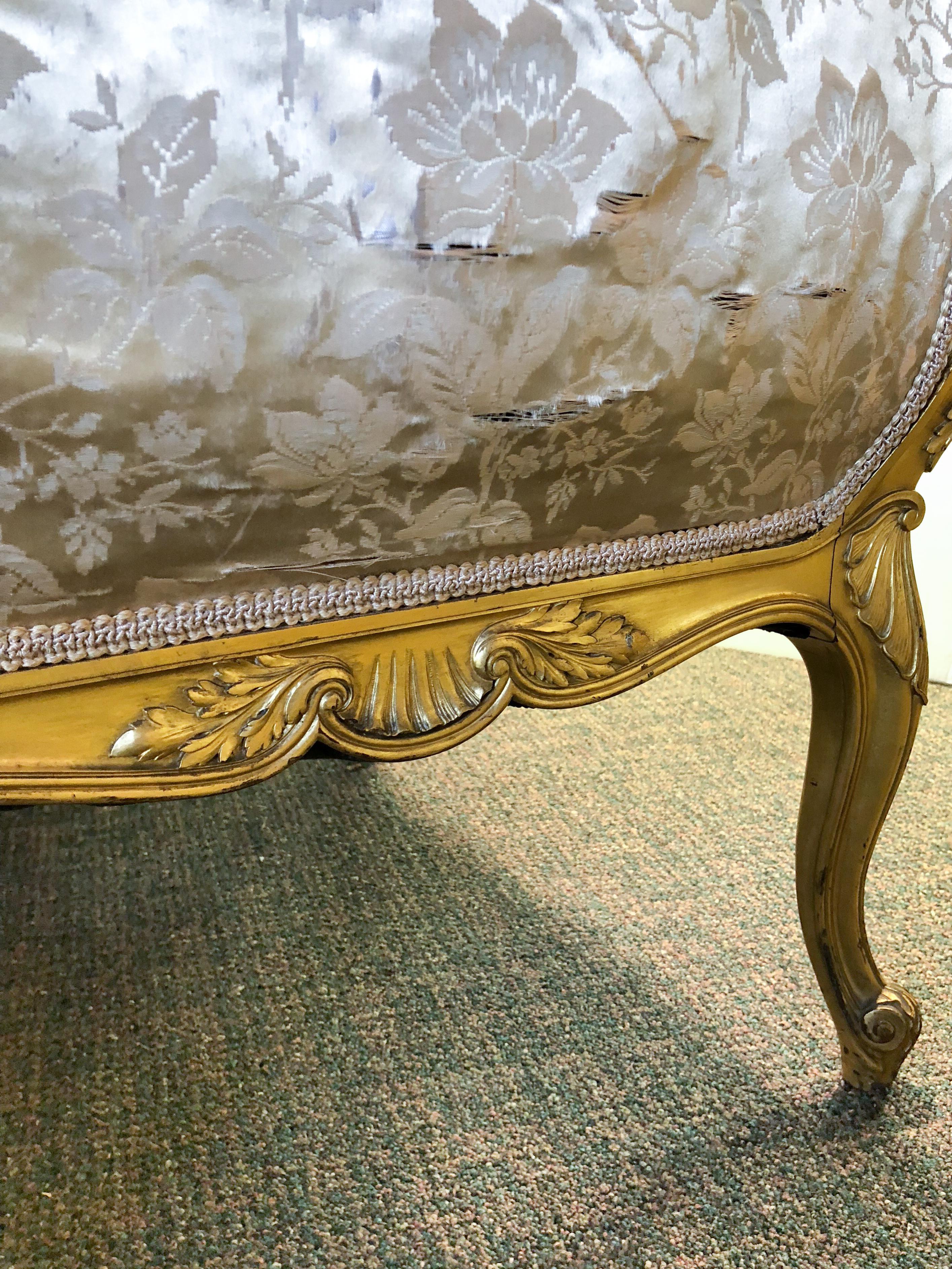 A 19th century Louis XV gilt carved mahogany settee with what appears to be original silk upholstery, horsehair stuffing and antique sprung seat. Beautifully carved mahogany frame, prime for reupholstery; some wear to gilding and frame consistent