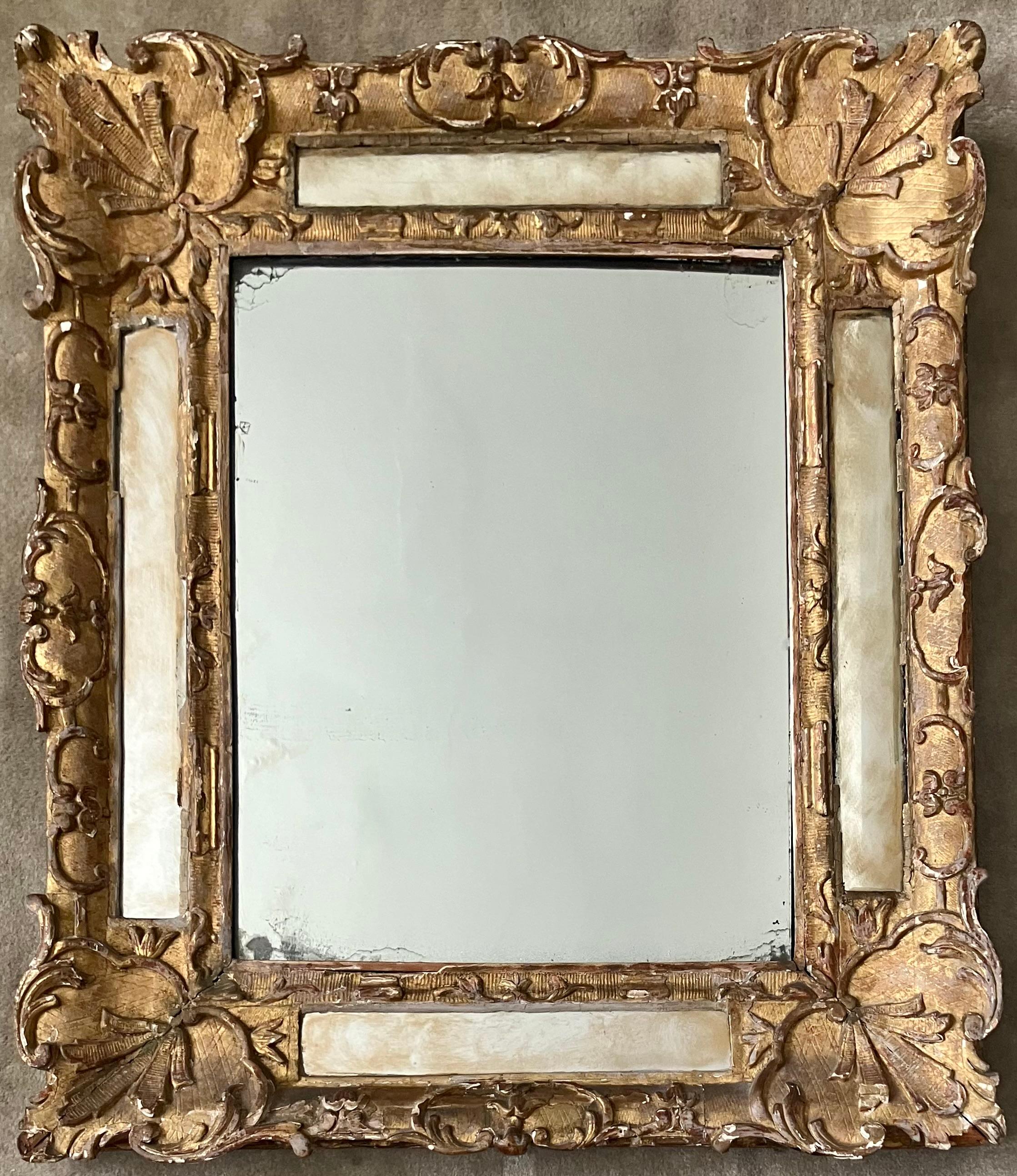 Specchio dorato Luigi XV. Specchio d'epoca Luigi XV in legno dorato intagliato e dipinto e gesso con ulteriori pannelli a specchio incastonati che delimitano il piatto centrale. Francia, metà del XVIII secolo. 
Dimensioni: 24