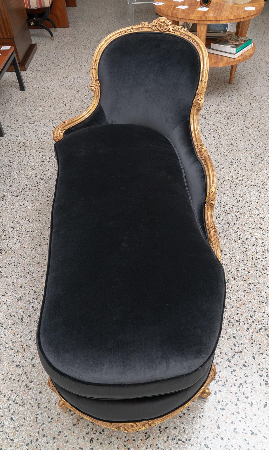 This stylish and chic Louis XV giltwood chaise was purchased for a Palm Beach collector in London and has been professionally restored and upholstered in a woven, black velvet upholstery.