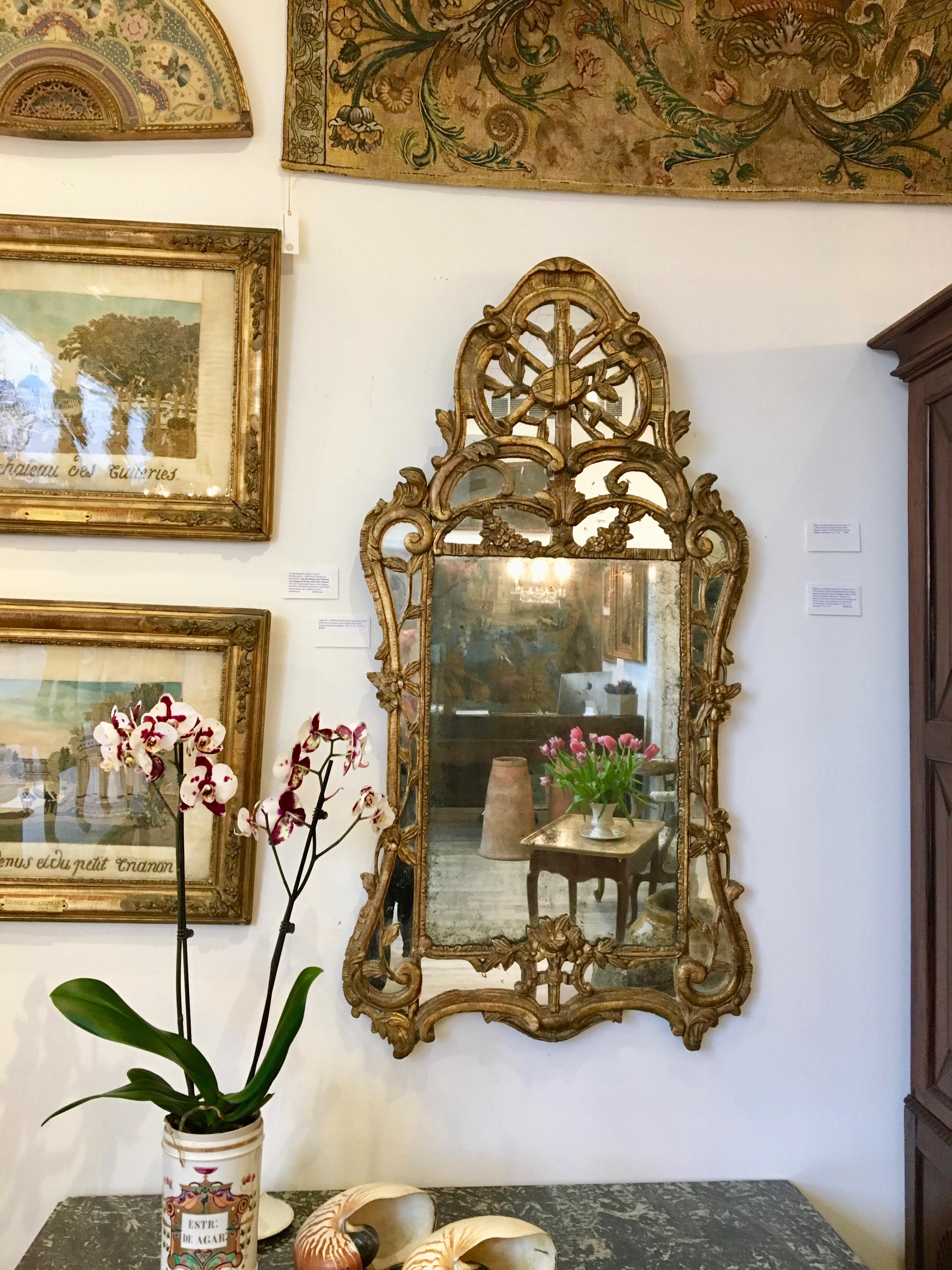 Louis XV circa 1750 Provincial, carved giltwood mirror with mirror borders, and scrolling foliate and musical motifs throughout. In excellent and overall original condition.