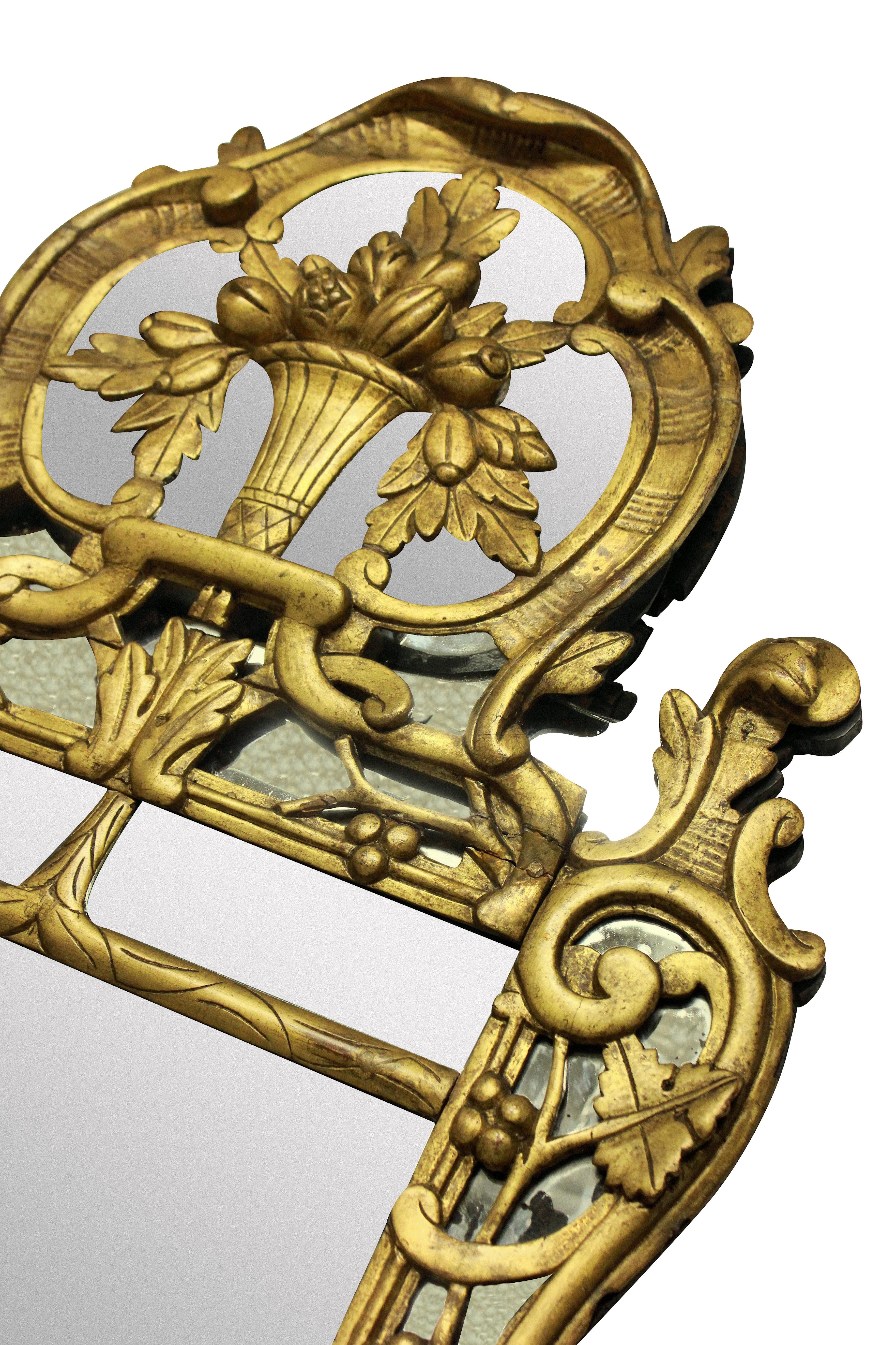 A French Louis XV mirror in carved giltwood, depicting foliage, with its original mercury plate. There is distressing around the edges but not in the middle of the mirror plate.

