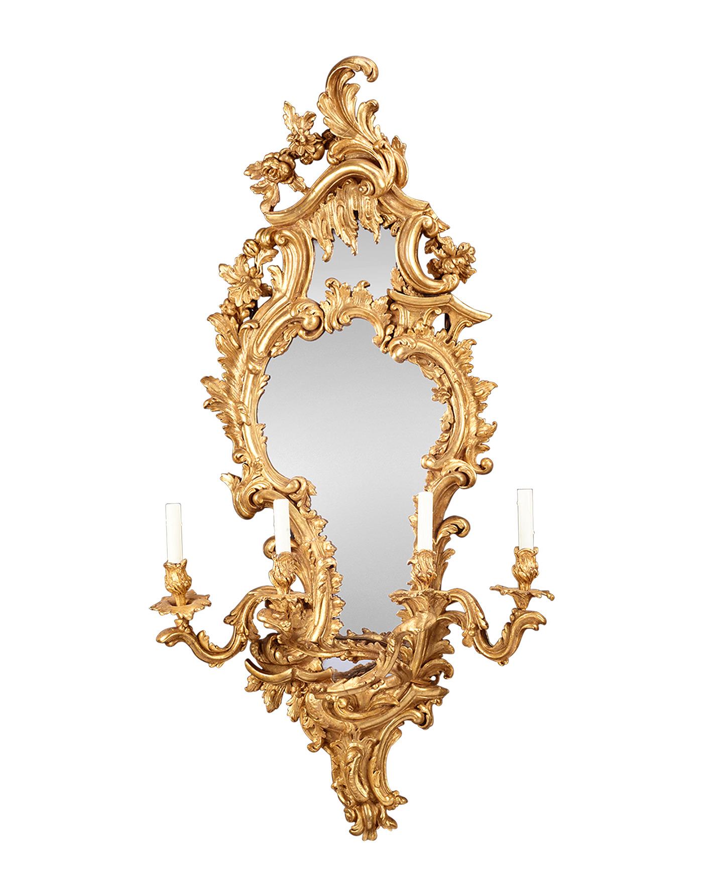 Cette paire incroyablement rare de girandoles à miroir en bois doré d'époque Louis XV reflète la grandeur, la grâce et l'opulence du mouvement rococo dans les arts décoratifs. Chaque miroir opulent est délicieusement encadré par de volumineux motifs