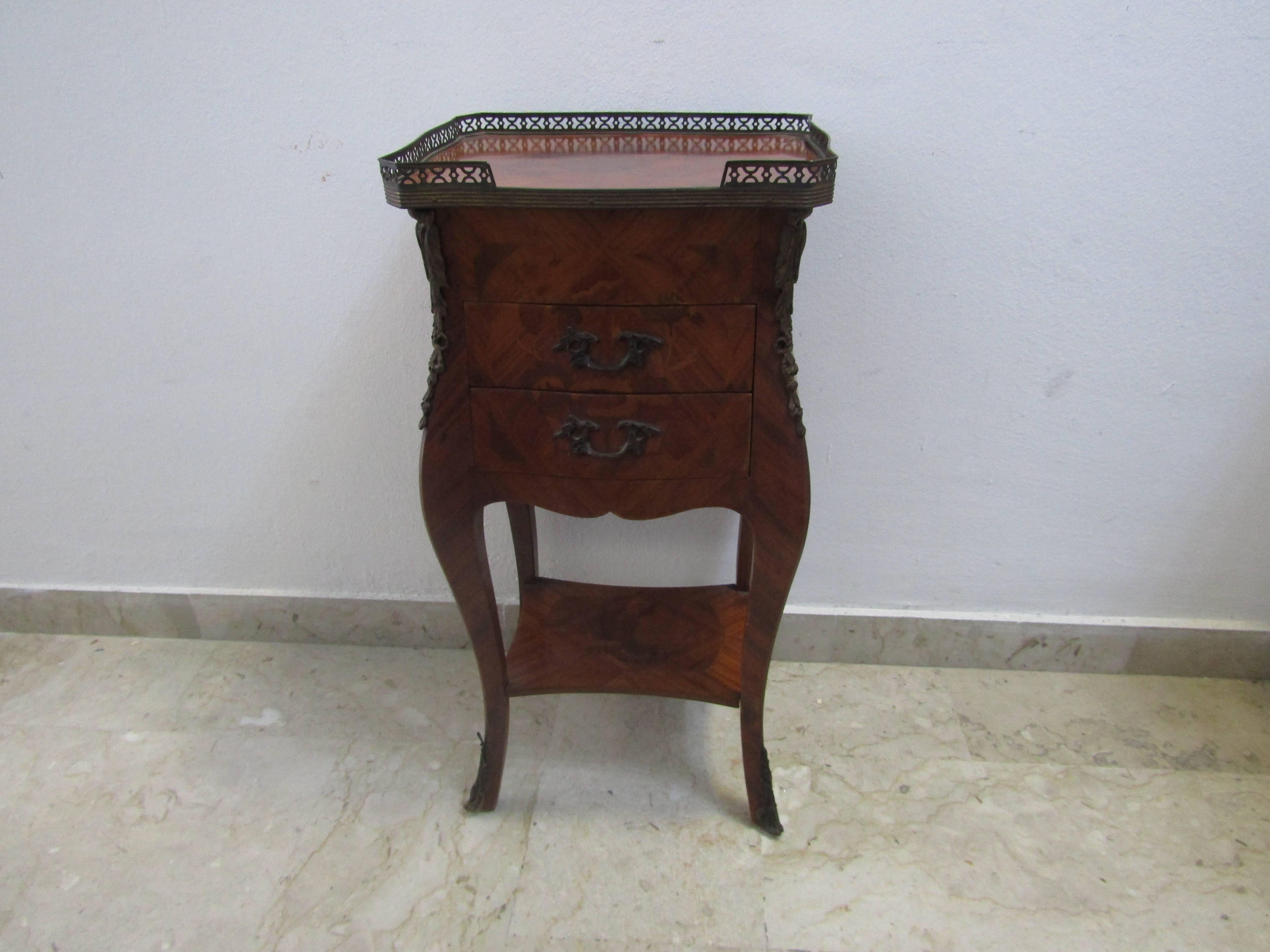 Elegant French bedside table. Beautiful finely inlaid piece of furniture with geometric patterns in rose wood decorated with chiseled and gilded bronzes. Coffee table of the twentieth century, equipped with a top shelf decorated with brass ring, a